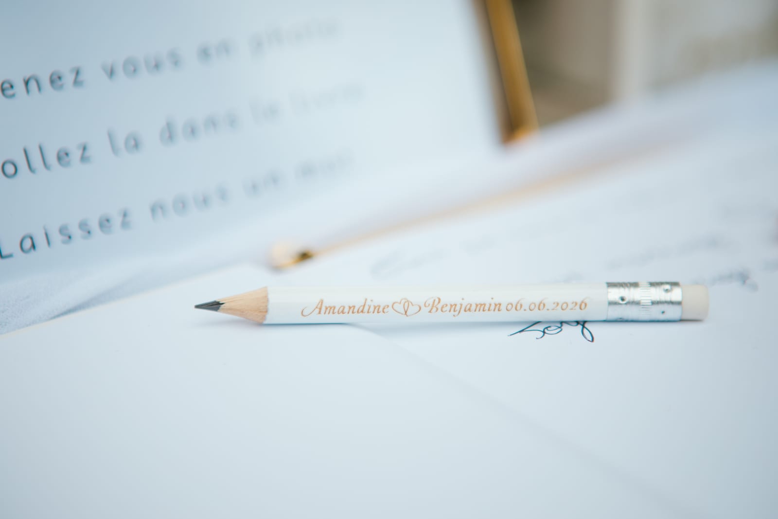 Crayon blanc personnalisé "Amandine & Benjamin 06.06.2026" posé sur le livre d'or des mariés, mariage au Domaine de Senercy, par Jean-Baptiste Argyre (Jaysphotography)
