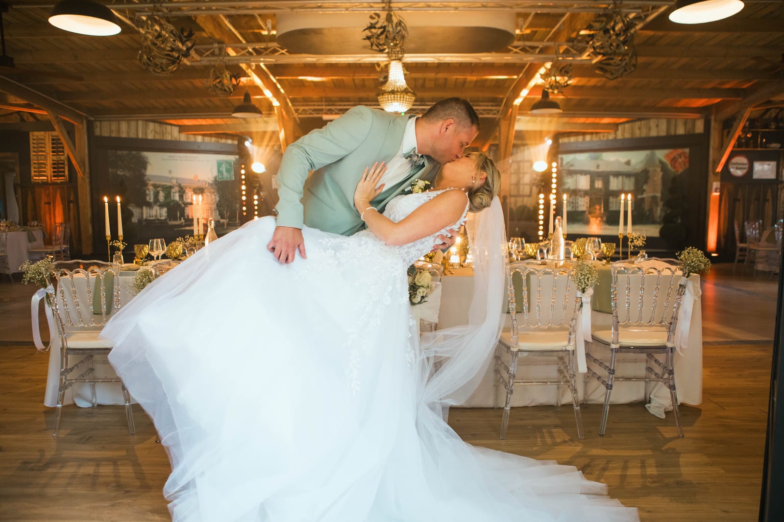 Benjamin penche Amandine pour l'embrasser au centre de la salle de réception, la traîne de la robe déployée, mariage au Domaine de Senercy, par Jean-Baptiste Argyre (Jaysphotography)