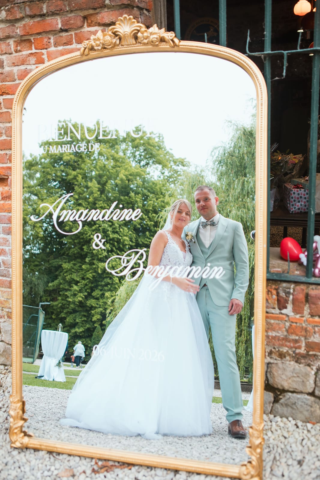 Amandine et Benjamin se reflètent dans le miroir-borne gravé "Livre d'or du mariage d'Amandine & Benjamin, 06 juin 2026", mariage au Domaine de Senercy, par Jean-Baptiste Argyre (Jaysphotography)