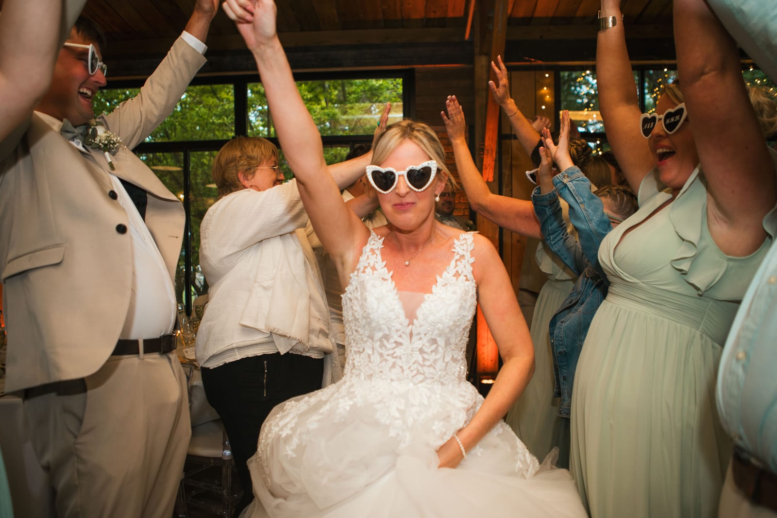 Amandine danse bras levés, lunettes en cœur sur les yeux, entourée de ses invités sur la piste, mariage au Domaine de Senercy, par Jean-Baptiste Argyre (Jaysphotography)