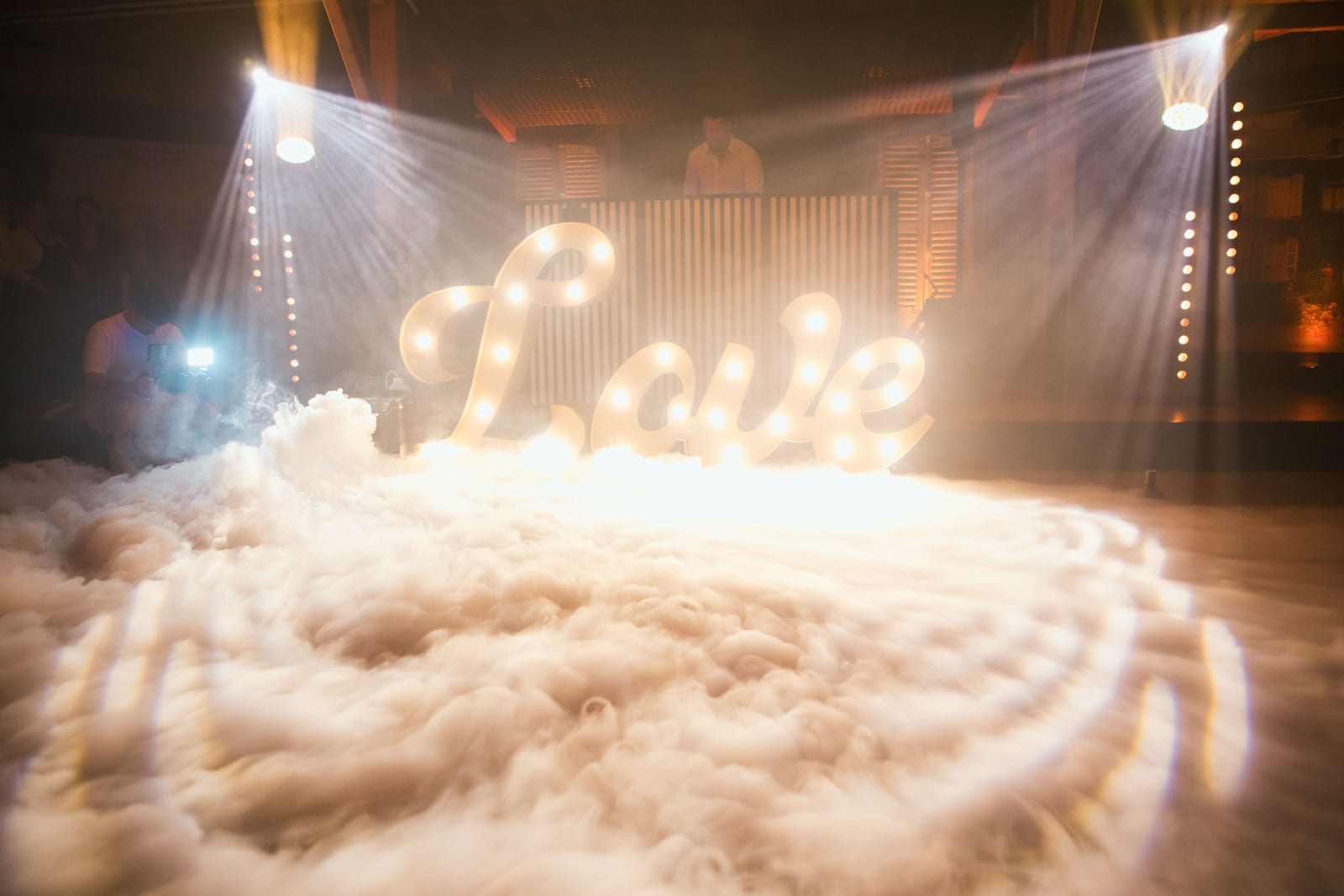 Ouverture de bal : les lettres lumineuses "Love" émergent d'un nuage de fumée bas baigné de faisceaux dorés, mariage au Domaine de Senercy, par Jean-Baptiste Argyre (Jaysphotography)