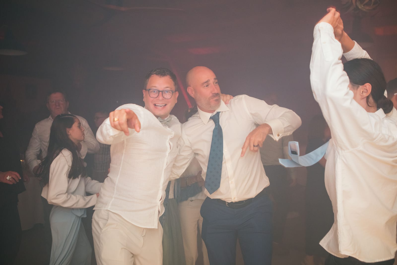 Deux invités en chemise blanche dansent avec énergie sous les lumières de la soirée, mariage au Domaine de Senercy, par Jean-Baptiste Argyre (Jaysphotography)
