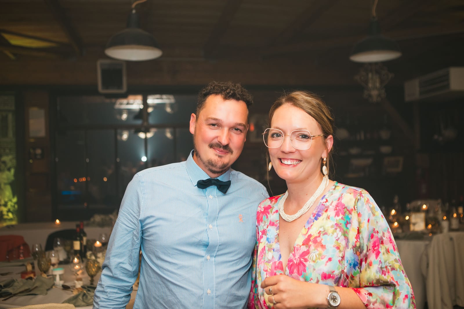 Un couple d'invités souriant pose dans la salle de réception en soirée, mariage au Domaine de Senercy, par Jean-Baptiste Argyre (Jaysphotography)