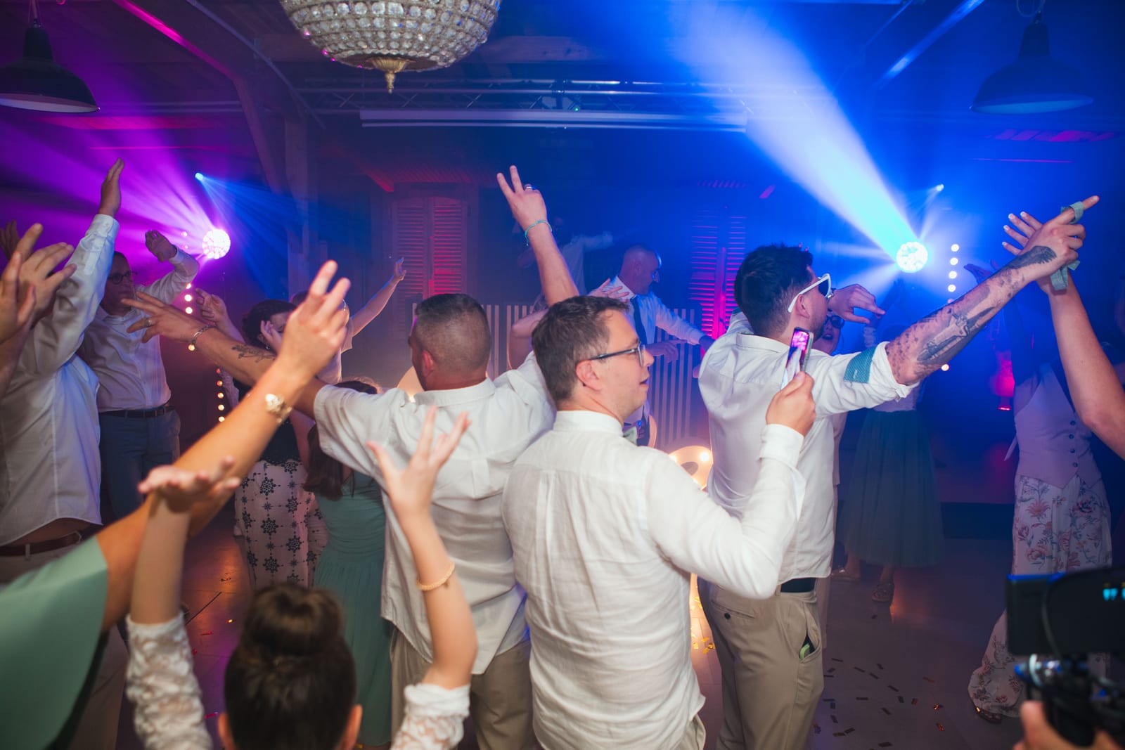 La piste de danse bondée, invités bras levés sous les lumières bleues et la fumée de la soirée, mariage au Domaine de Senercy, par Jean-Baptiste Argyre (Jaysphotography)