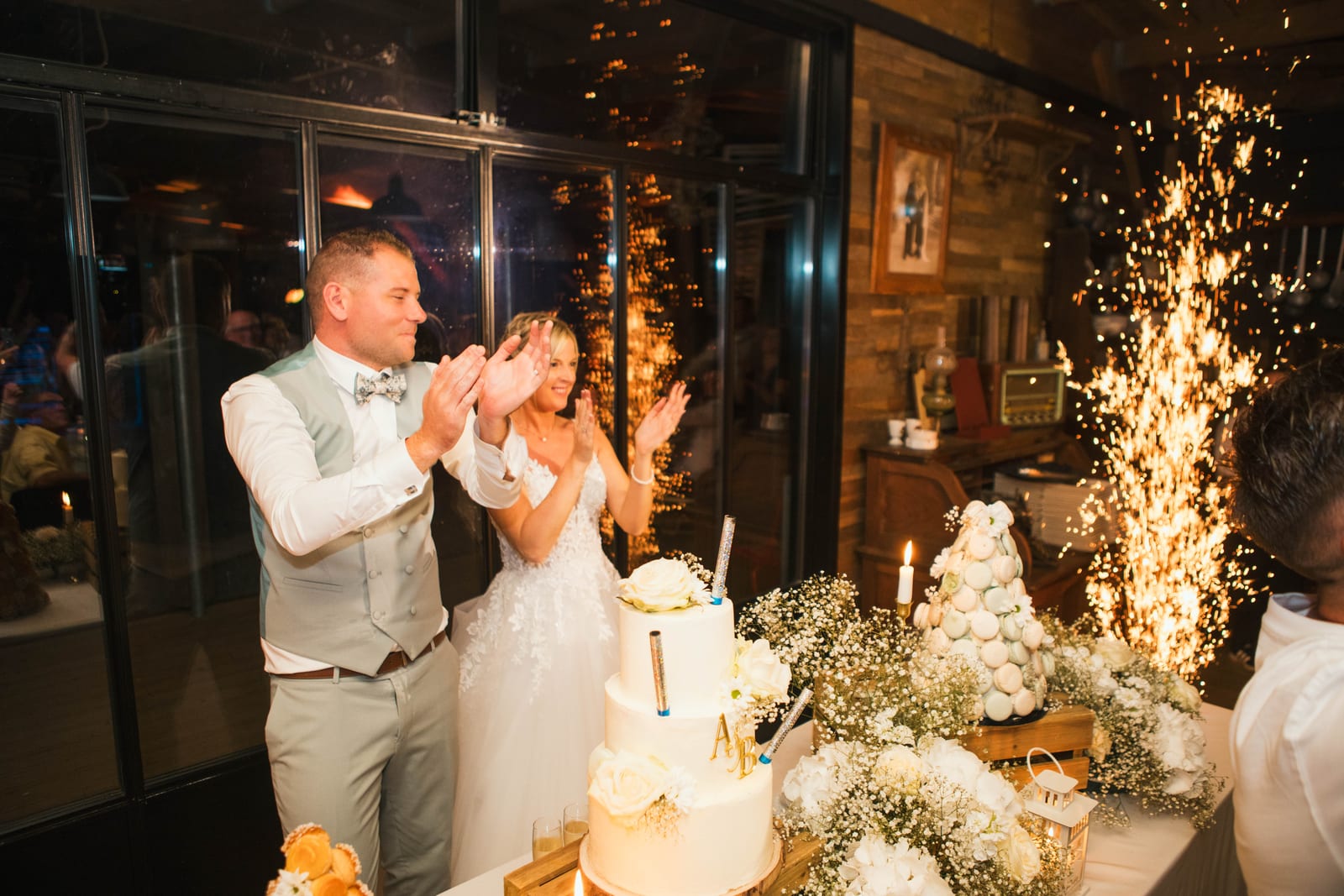 Amandine et Benjamin applaudissent devant leur gâteau et leur pièce montée, fontaine d'étincelles à l'arrière, mariage au Domaine de Senercy, par Jean-Baptiste Argyre (Jaysphotography)