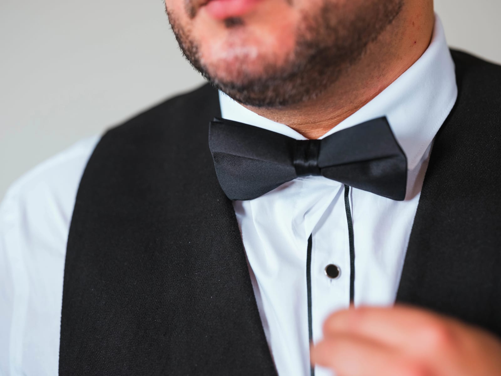 Gros plan sur le nœud papillon de satin noir, la chemise à plastron et le gilet noir du marié pendant les préparatifs, mariage au Château de Montvillargenne, Gouvieux, par Jean-Baptiste Argyre (Jaysphotography)