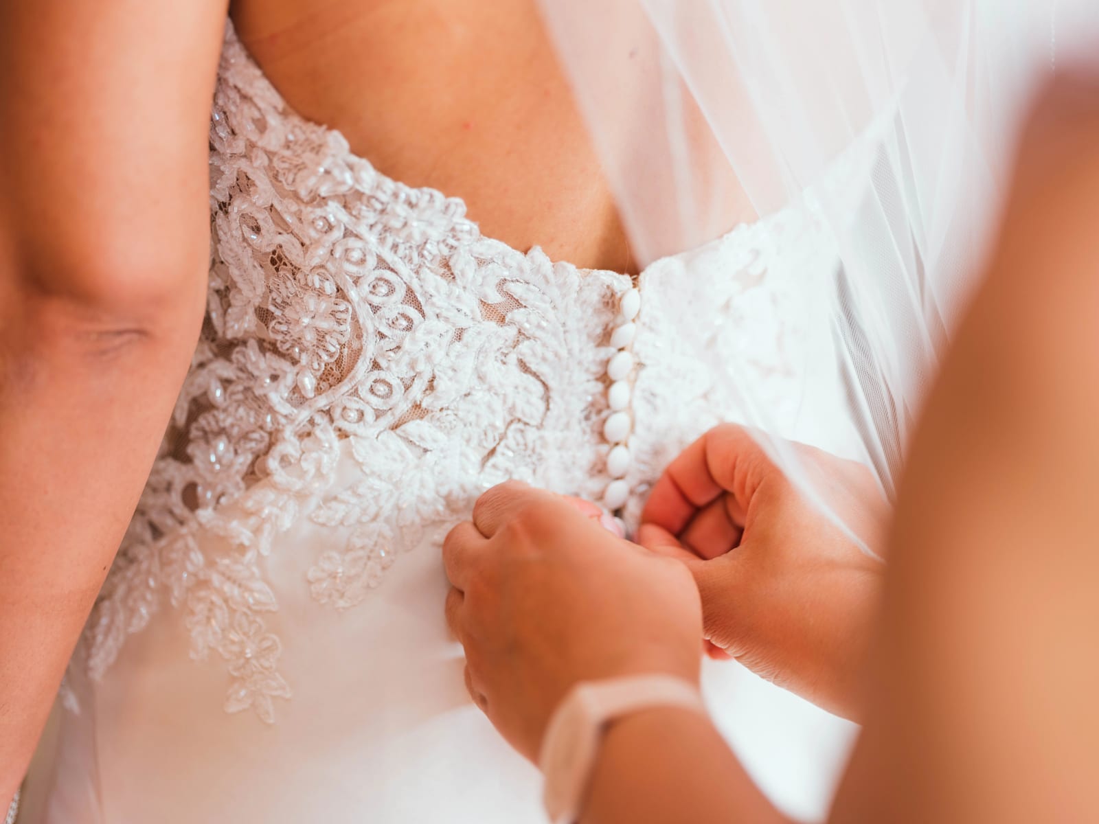 On boutonne le dos en dentelle brodée de perles de la robe de mariée, gros plan, mariage au Château de Montvillargenne, Gouvieux, par Jean-Baptiste Argyre (Jaysphotography)