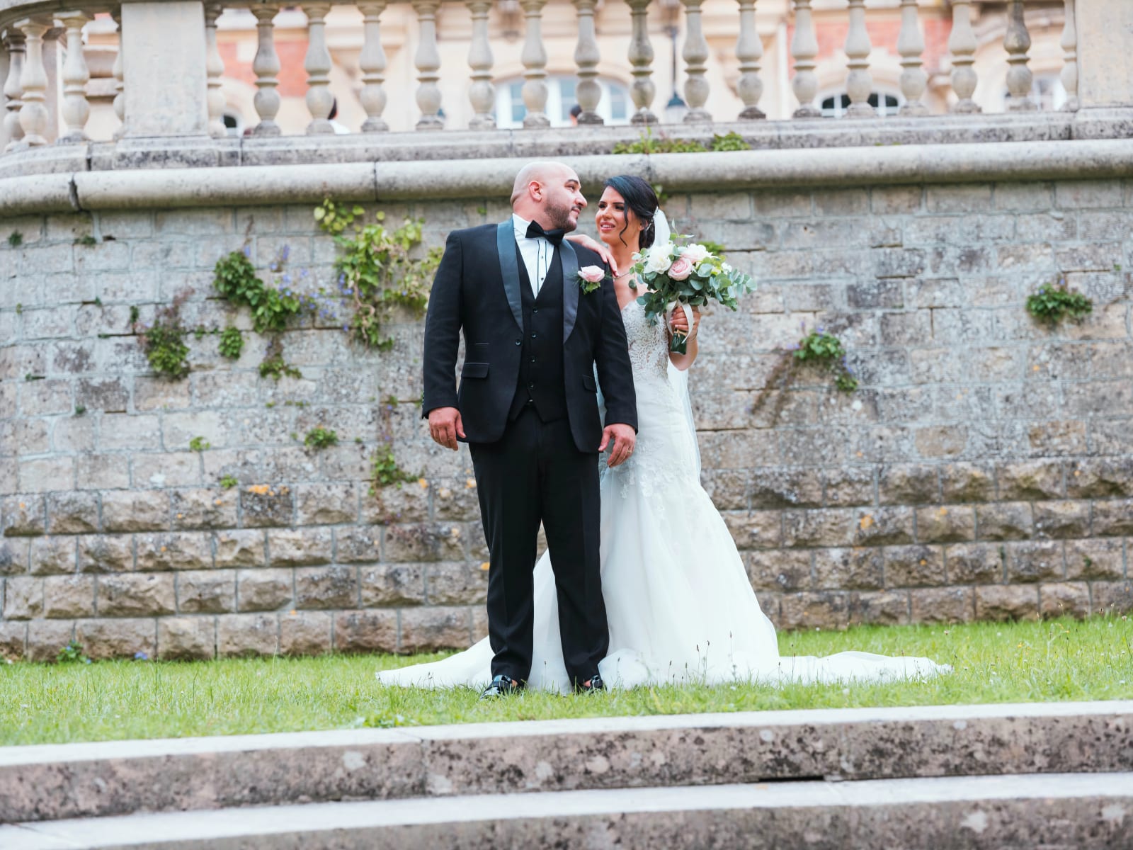 Les mariés au pied d'un mur de pierre couvert de lierre sous les balustres de la terrasse, Gouvieux, mariage au Château de Montvillargenne, Gouvieux, par Jean-Baptiste Argyre (Jaysphotography)