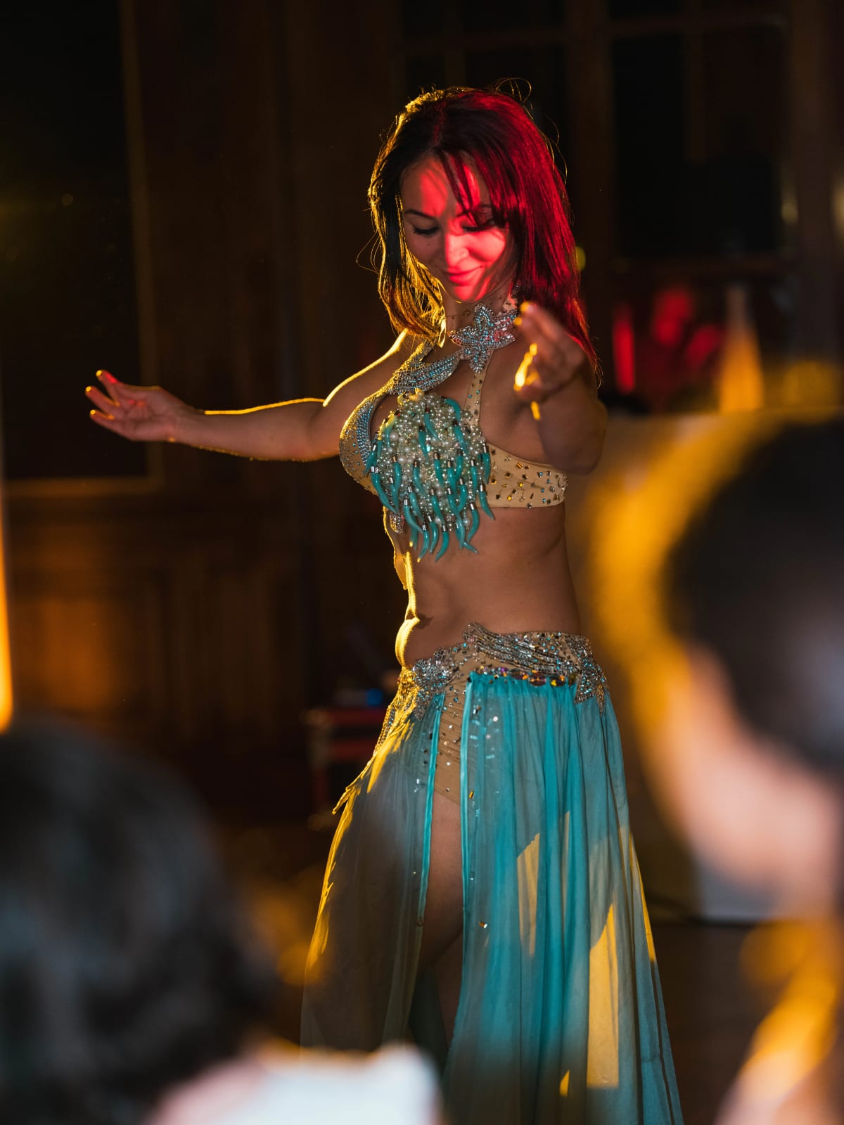 Une danseuse orientale en costume turquoise brodé de perles danse parmi les invités dans une salle aux boiseries sombres, mariage au Château de Montvillargenne, Gouvieux, par Jean-Baptiste Argyre (Jaysphotography)