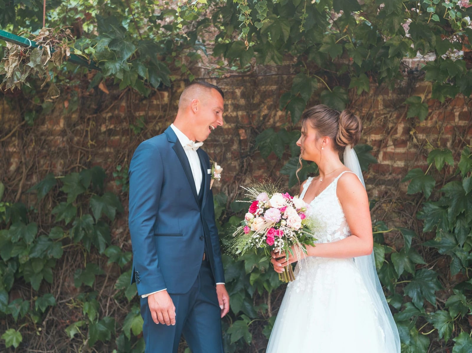 Amélie et Guillaume se découvrent face à face devant le mur de lierre du domaine, mariage au Les Voûtes du Plessier, par Jean-Baptiste Argyre (Jaysphotography)