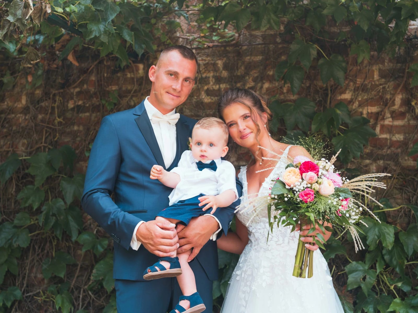 Amélie et Guillaume avec leur fils dans les bras avant la cérémonie civile, bouquet à la main, mariage au Les Voûtes du Plessier, par Jean-Baptiste Argyre (Jaysphotography)