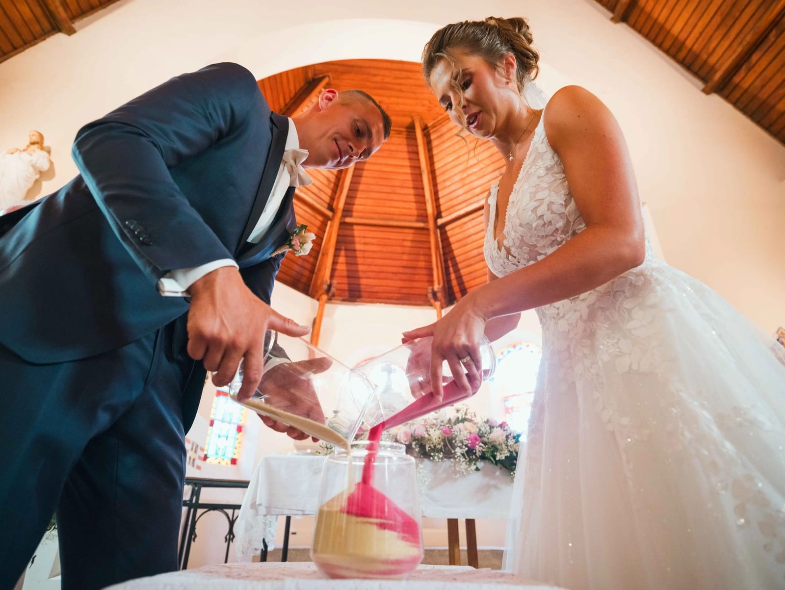 Rituel du sable : Amélie et Guillaume versent ensemble deux sables de couleur dans le même vase, mariage au Les Voûtes du Plessier, par Jean-Baptiste Argyre (Jaysphotography)