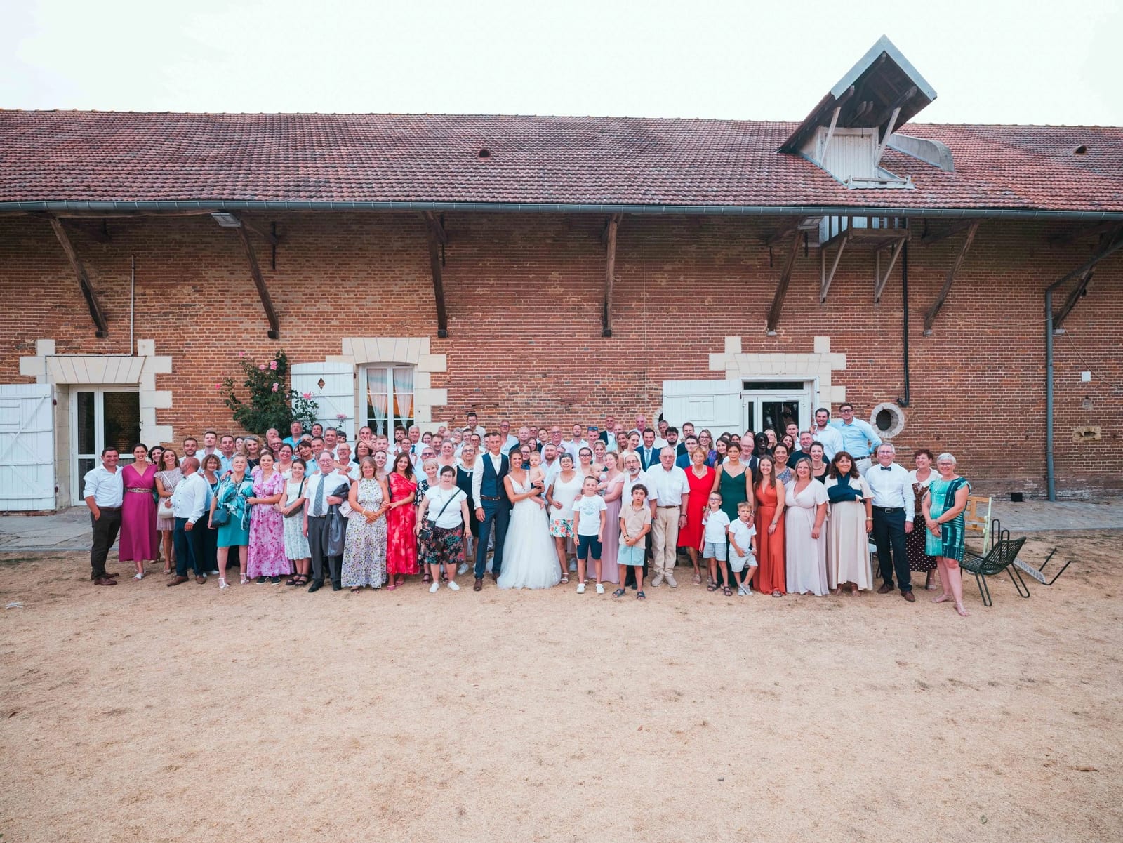 Les 250 invités rangés sur toute la façade de brique des Voûtes du Plessier autour des mariés, mariage au Les Voûtes du Plessier, par Jean-Baptiste Argyre (Jaysphotography)