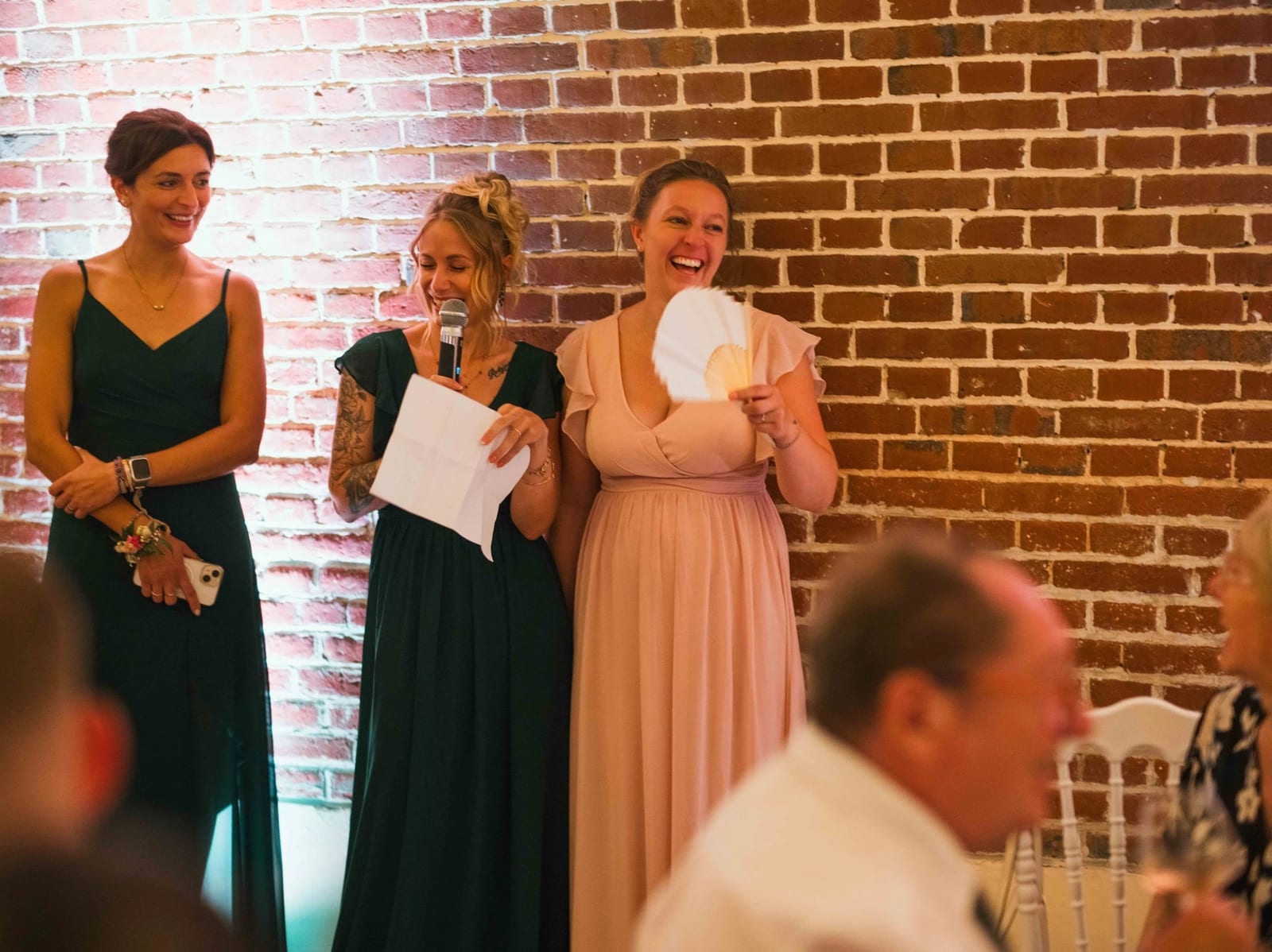 Les demoiselles d'honneur lisent leur discours, feuilles à la main, contre le mur de brique de la salle voûtée, mariage au Les Voûtes du Plessier, par Jean-Baptiste Argyre (Jaysphotography)