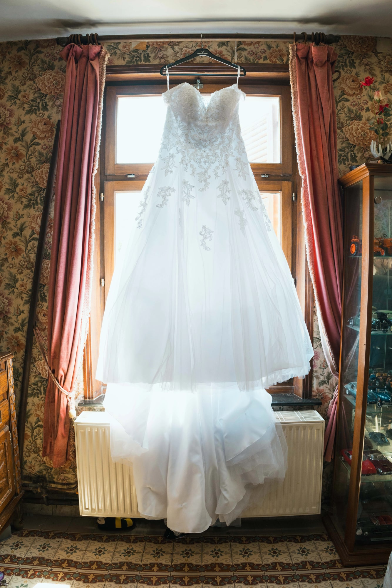 Robe de mariée suspendue à la fenêtre pendant les préparatifs à Floyon, mariage au Buironfosse (Aisne), par Jean-Baptiste Argyre (Jaysphotography)