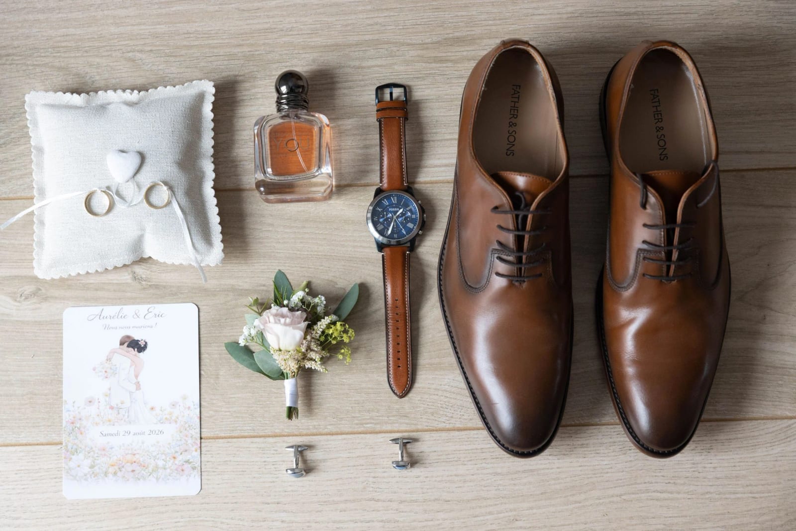 Les affaires du marié posées à plat : coussin d'alliances brodé, parfum, montre à cadran bleu, souliers de cuir fauve, boutons de manchette et faire-part, préparatifs à La Mézandrée, mariage au La Mézandrée, par Jean-Baptiste Argyre (Jaysphotography)
