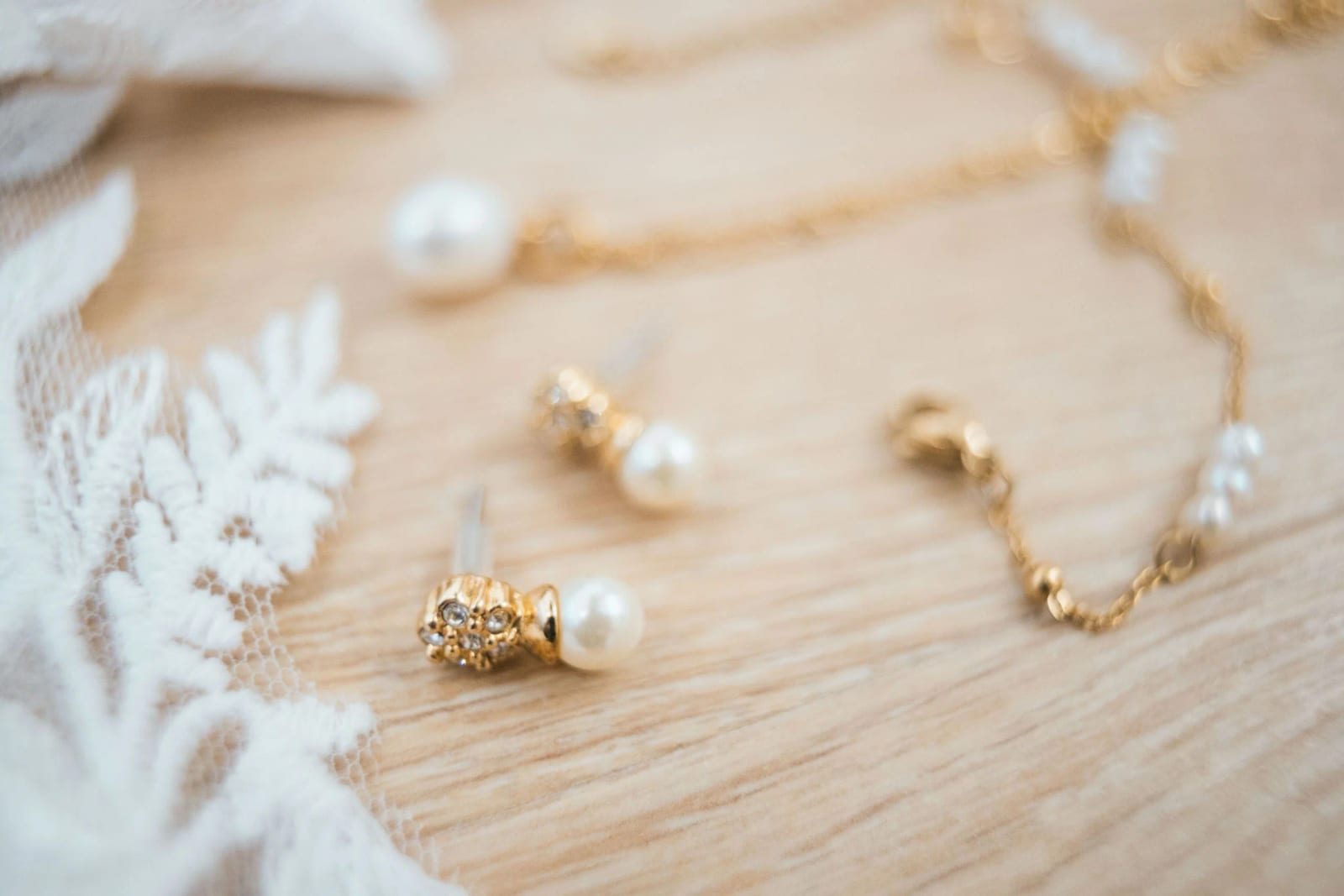 Boucles d'oreilles et collier de perles blanches montées sur or posés sur la dentelle de la robe, mariage à La Mézandrée, mariage au La Mézandrée, par Jean-Baptiste Argyre (Jaysphotography)