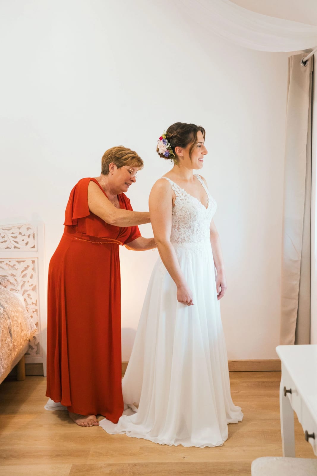 La mère de la mariée, en robe terracotta, ferme la robe dans son dos pendant l'habillage, mariage d'Aurélie et Éric, mariage au La Mézandrée, par Jean-Baptiste Argyre (Jaysphotography)