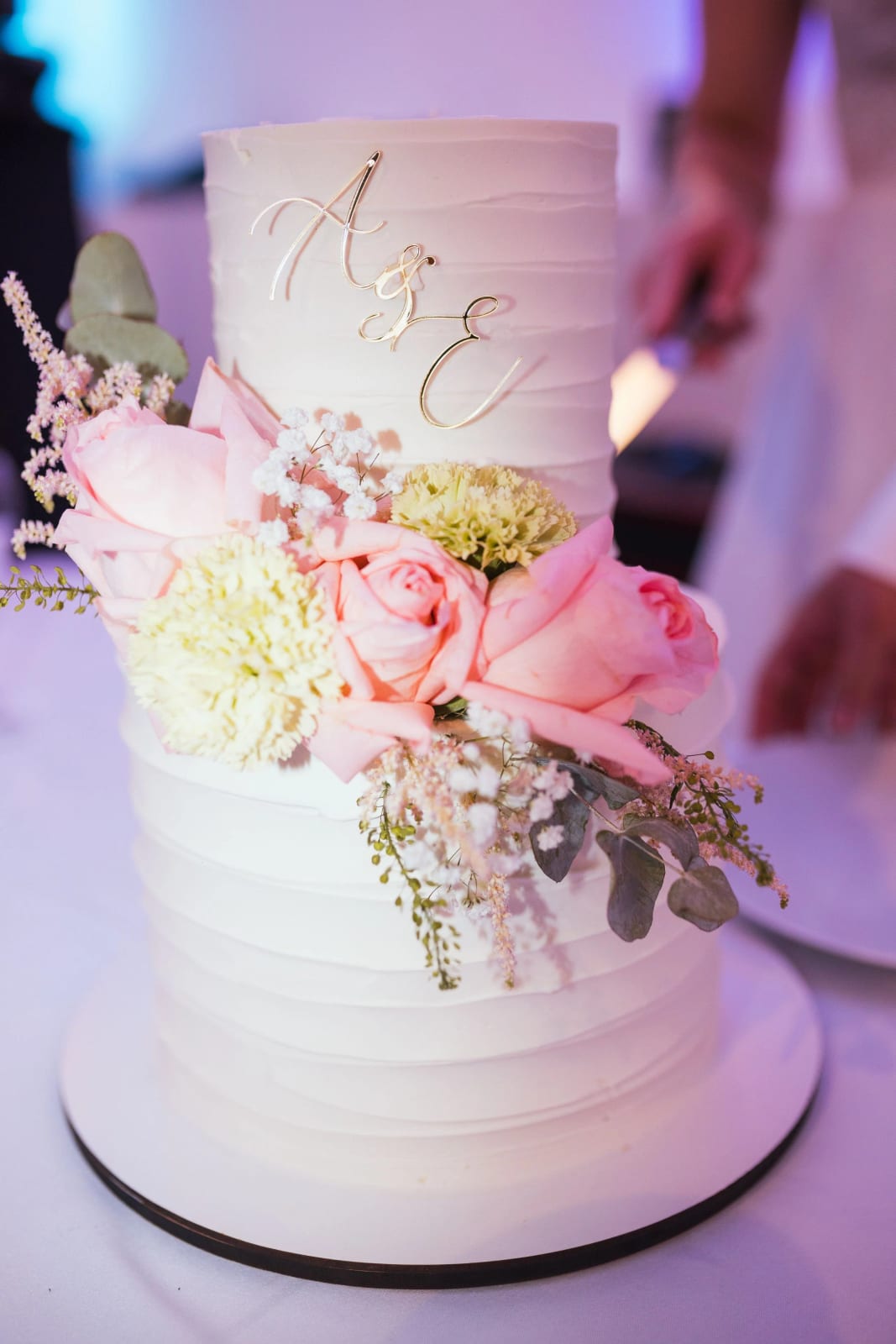 Le wedding cake blanc à deux étages, initiales A et E en fil doré, roses roses et feuillage gris-vert, mariage à La Mézandrée, mariage au La Mézandrée, par Jean-Baptiste Argyre (Jaysphotography)