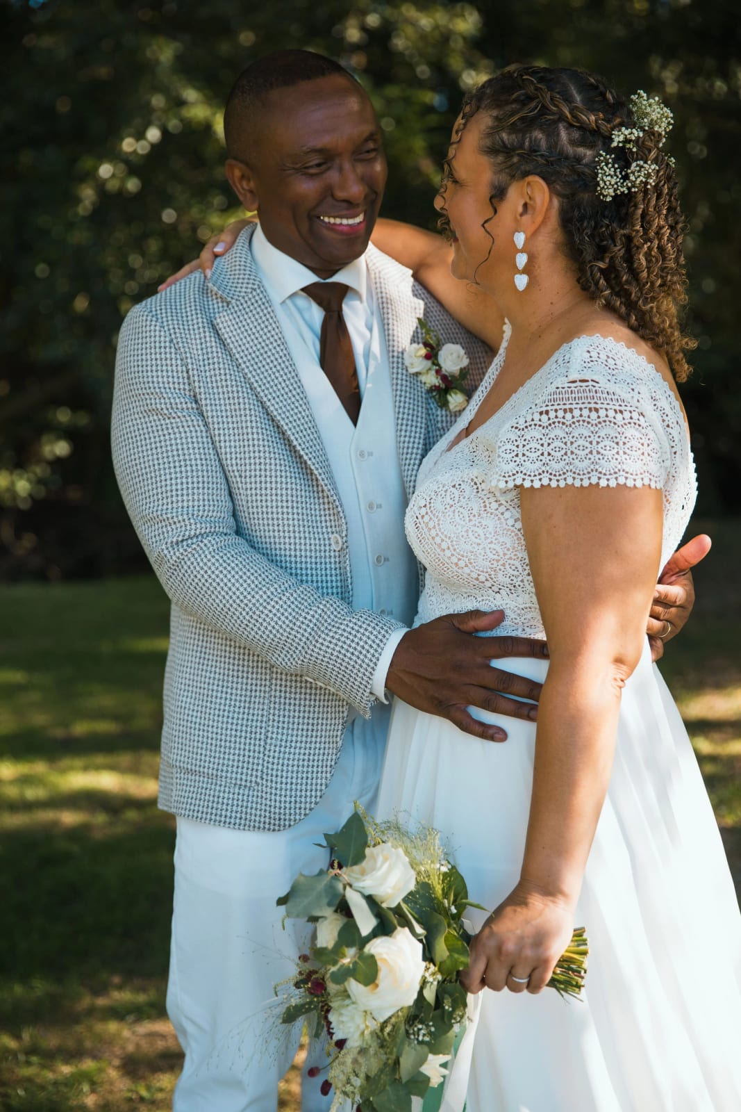 Les mariés enlacés et souriants sous les arbres, bouquet de roses blanches et d'eucalyptus, mariage au Château de la Houssoye, par Jean-Baptiste Argyre (Jaysphotography)