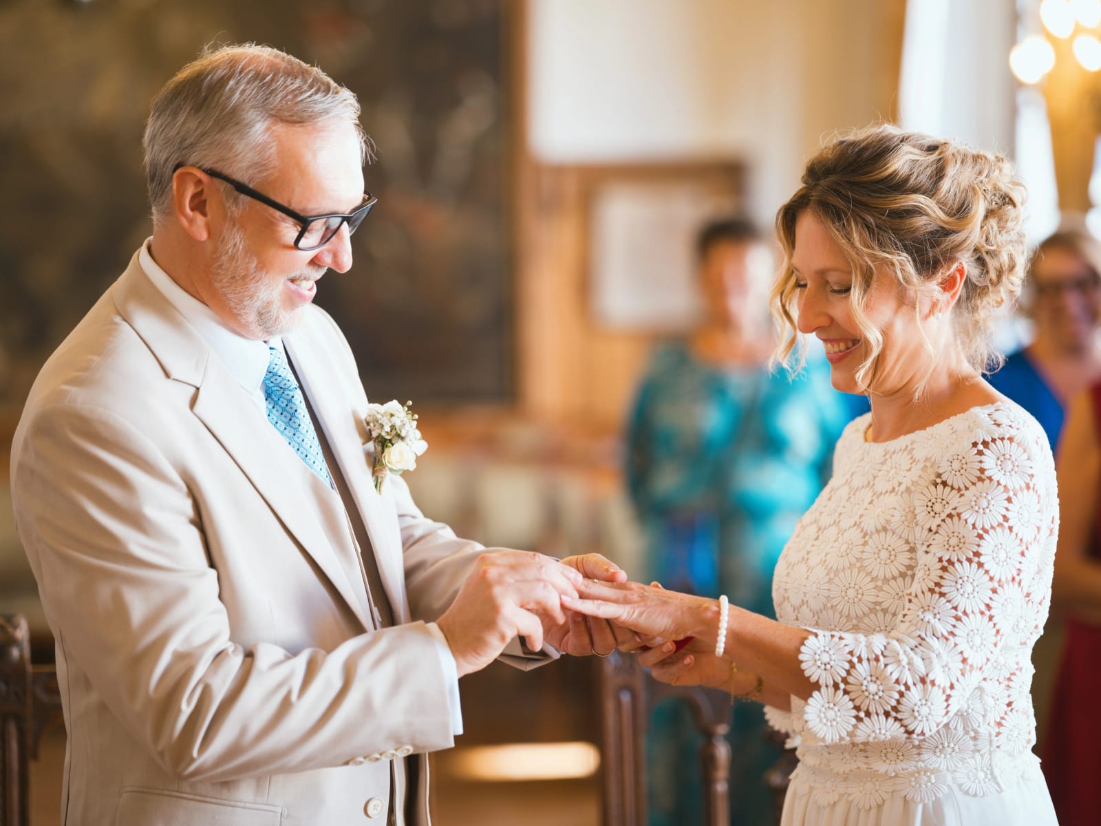 Échange des alliances dans la salle des mariages, le marié en costume beige et cravate turquoise glisse l'alliance au doigt de la mariée, mariage à la Mairie de Senlis, par Jean-Baptiste Argyre (Jaysphotography)