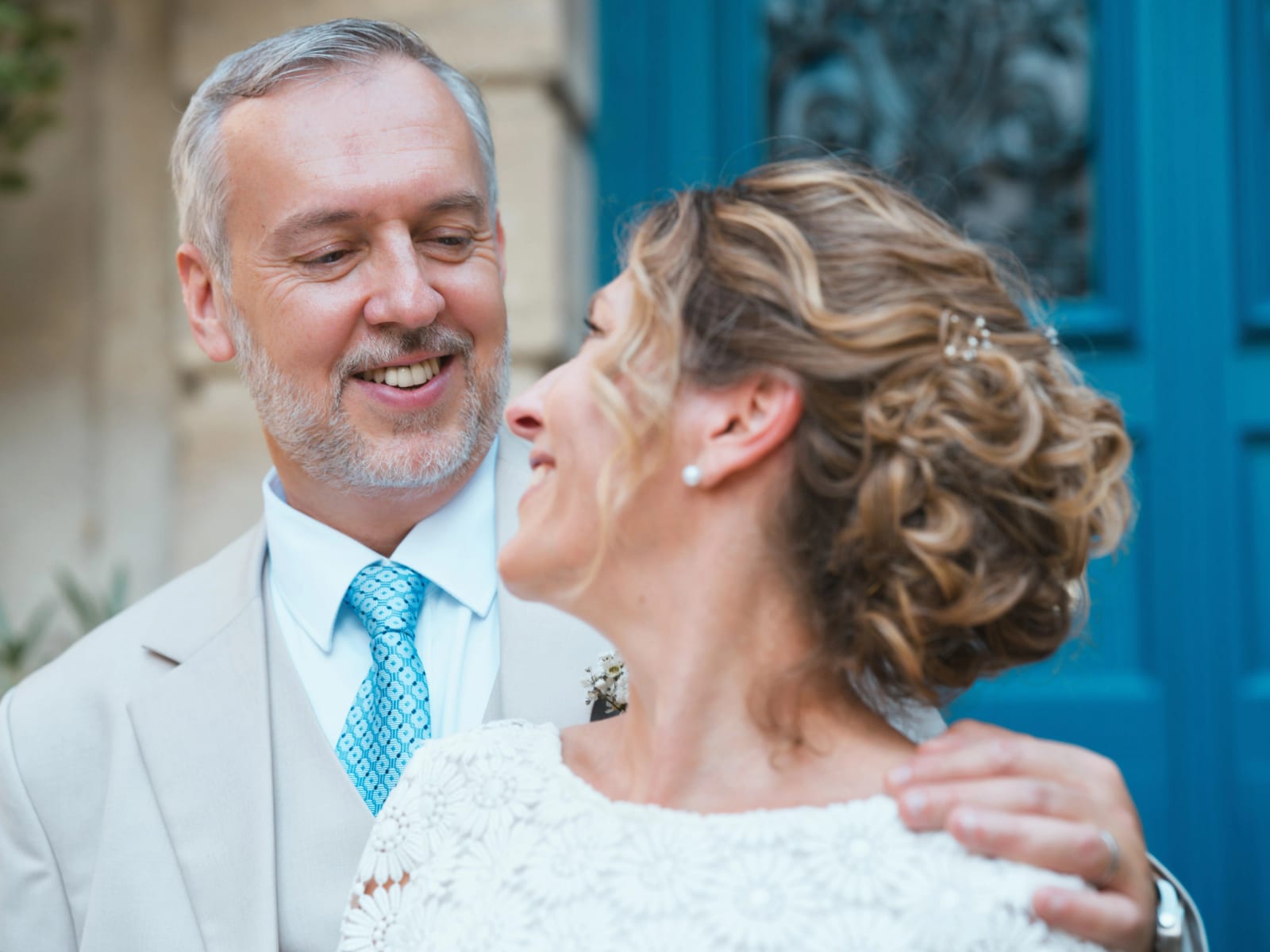 Portrait serré des mariés souriants devant une porte peinte en bleu vif, mariage à la Mairie de Senlis, par Jean-Baptiste Argyre (Jaysphotography)