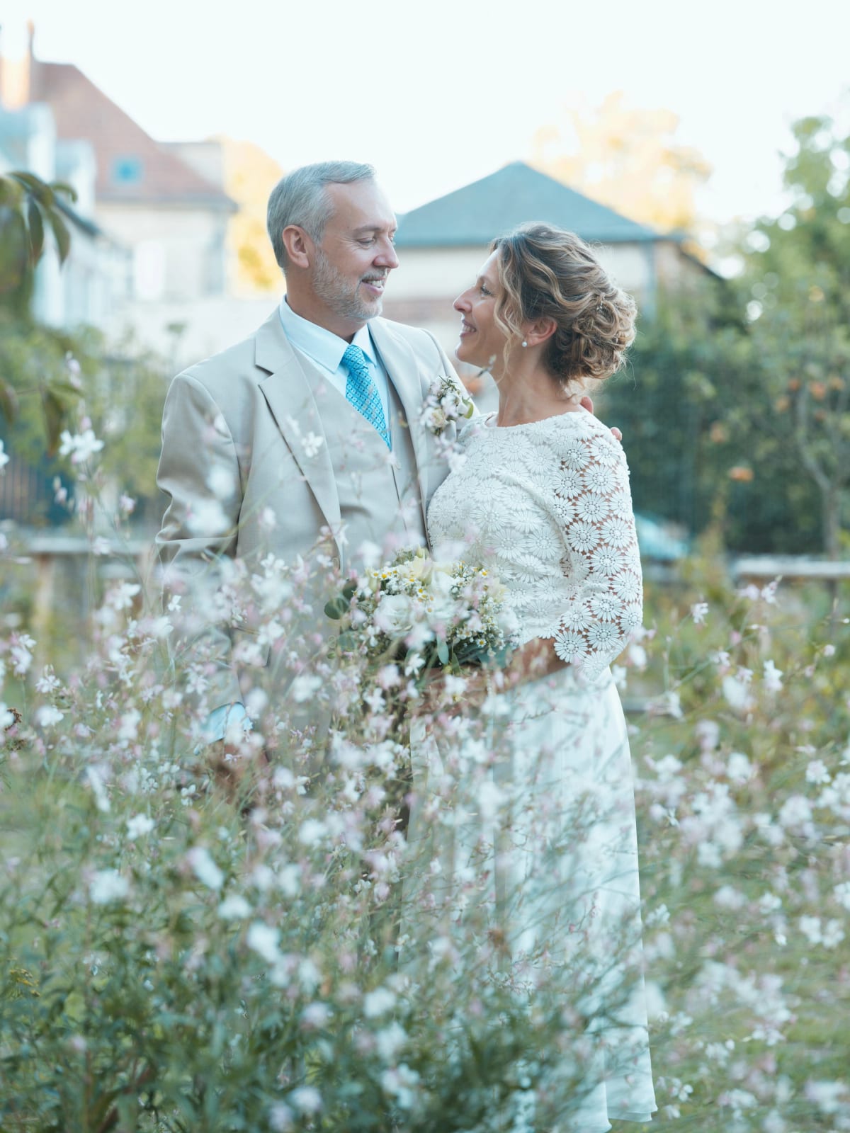 Les mariés se regardent au milieu de fleurs blanches et roses légères, lumière de fin de journée, mariage à la Mairie de Senlis, par Jean-Baptiste Argyre (Jaysphotography)