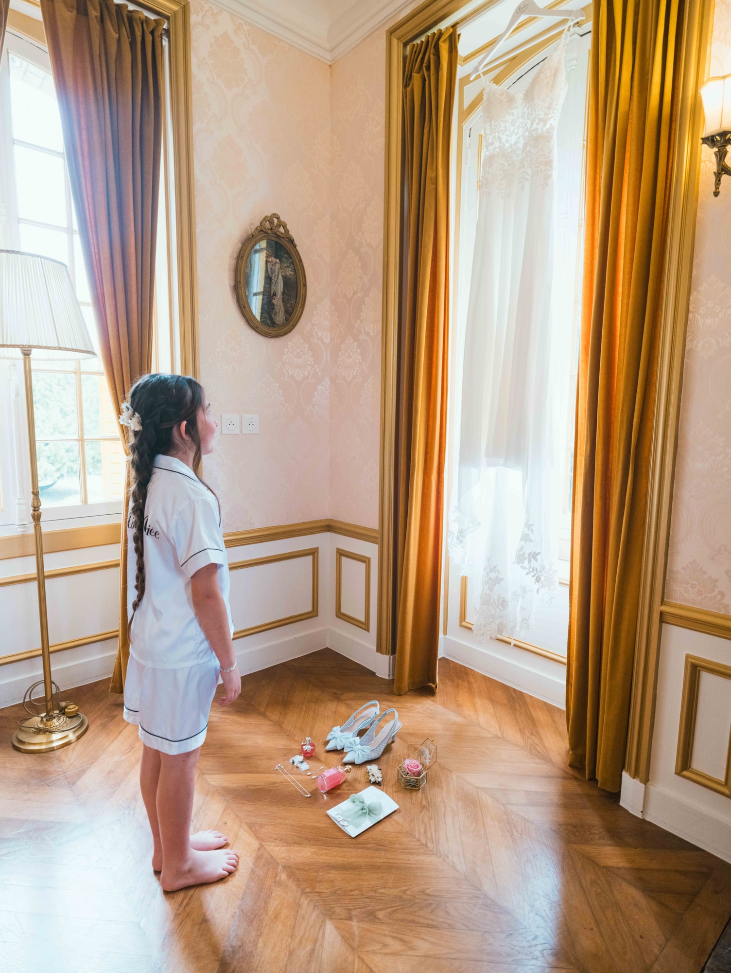 Emmy regardant la robe de sa maman suspendue dans la chambre dorée du château, mariage au Château de Moliens, par Jean-Baptiste Argyre (Jaysphotography)