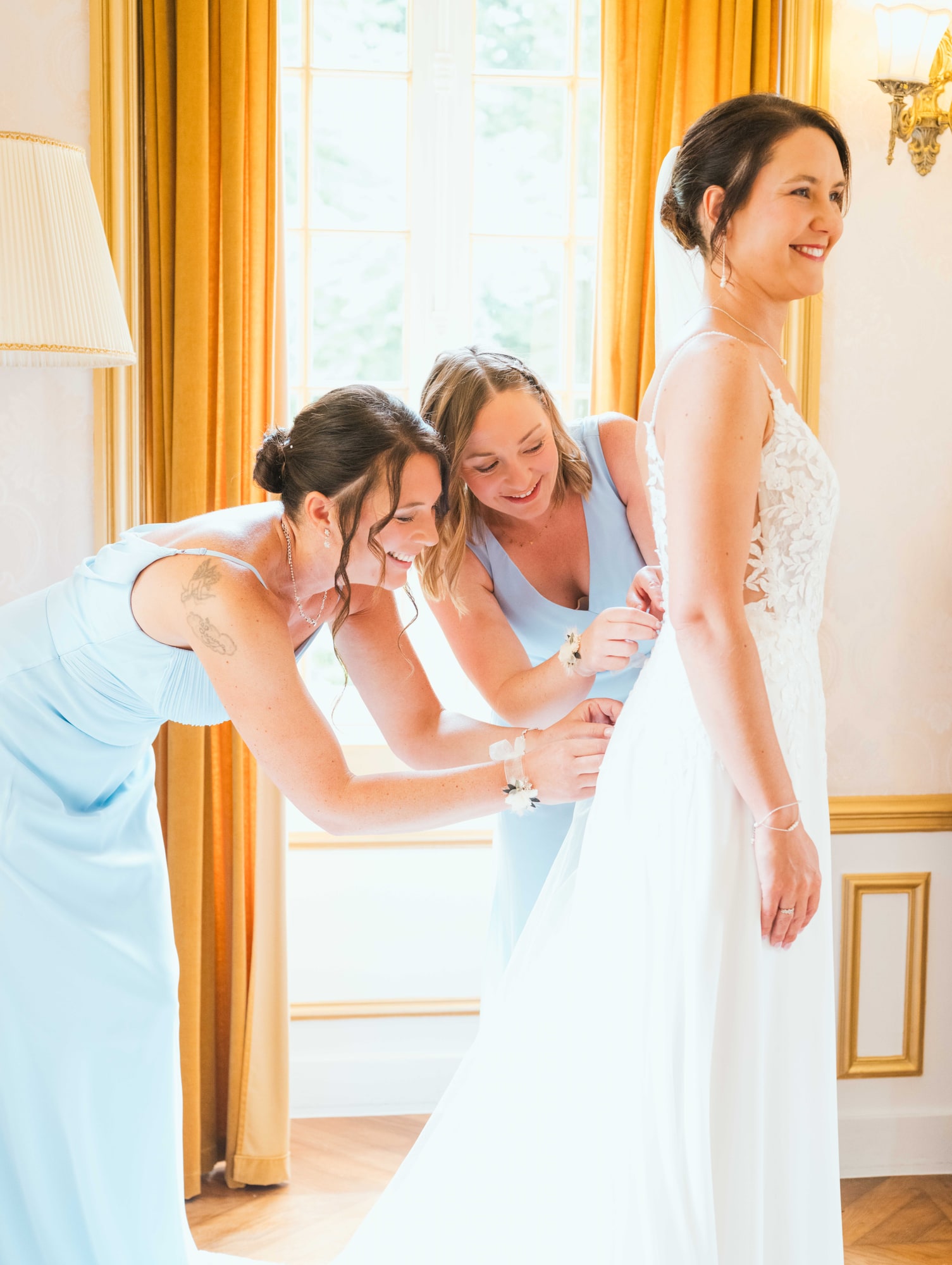 Le laçage de la robe de Charline par ses demoiselles en bleu ciel, mariage au Château de Moliens, par Jean-Baptiste Argyre (Jaysphotography)