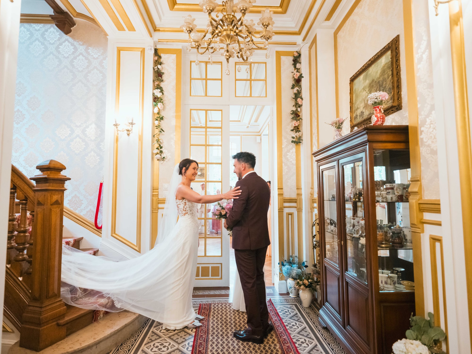 Le first look de Charline et Jonathan au pied de l'escalier doré du château, mariage au Château de Moliens, par Jean-Baptiste Argyre (Jaysphotography)