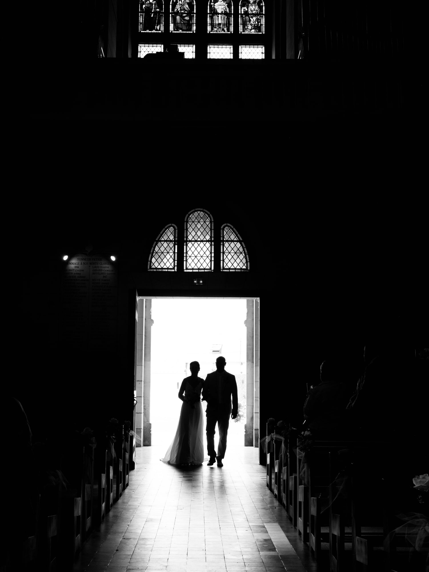 Silhouette des mariés en noir et blanc dans le portail de l'église de Formerie, mariage au Château de Moliens, par Jean-Baptiste Argyre (Jaysphotography)