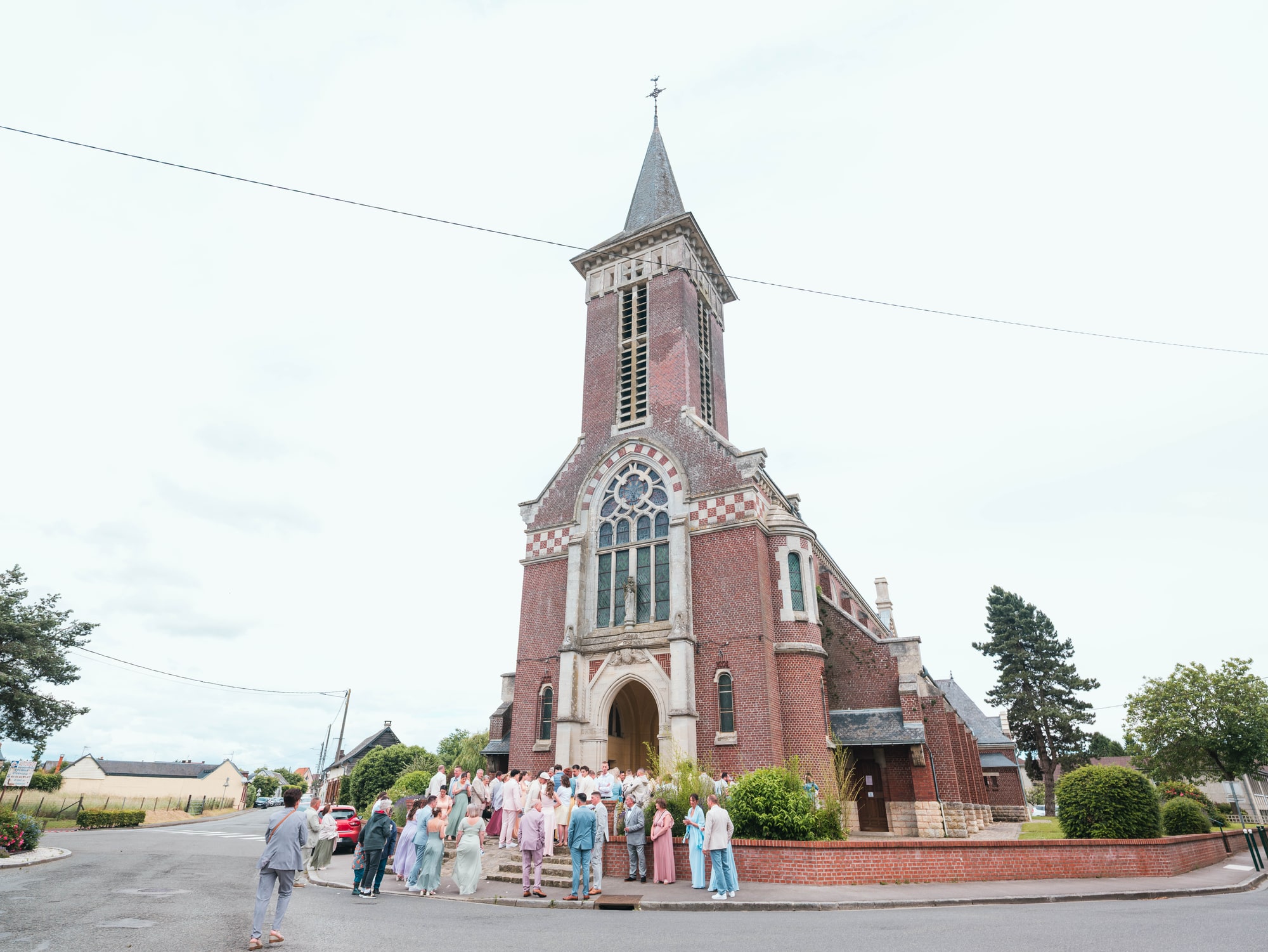 L'église de brique de Formerie et les invités rassemblés, mariage au Château de Moliens, par Jean-Baptiste Argyre (Jaysphotography)