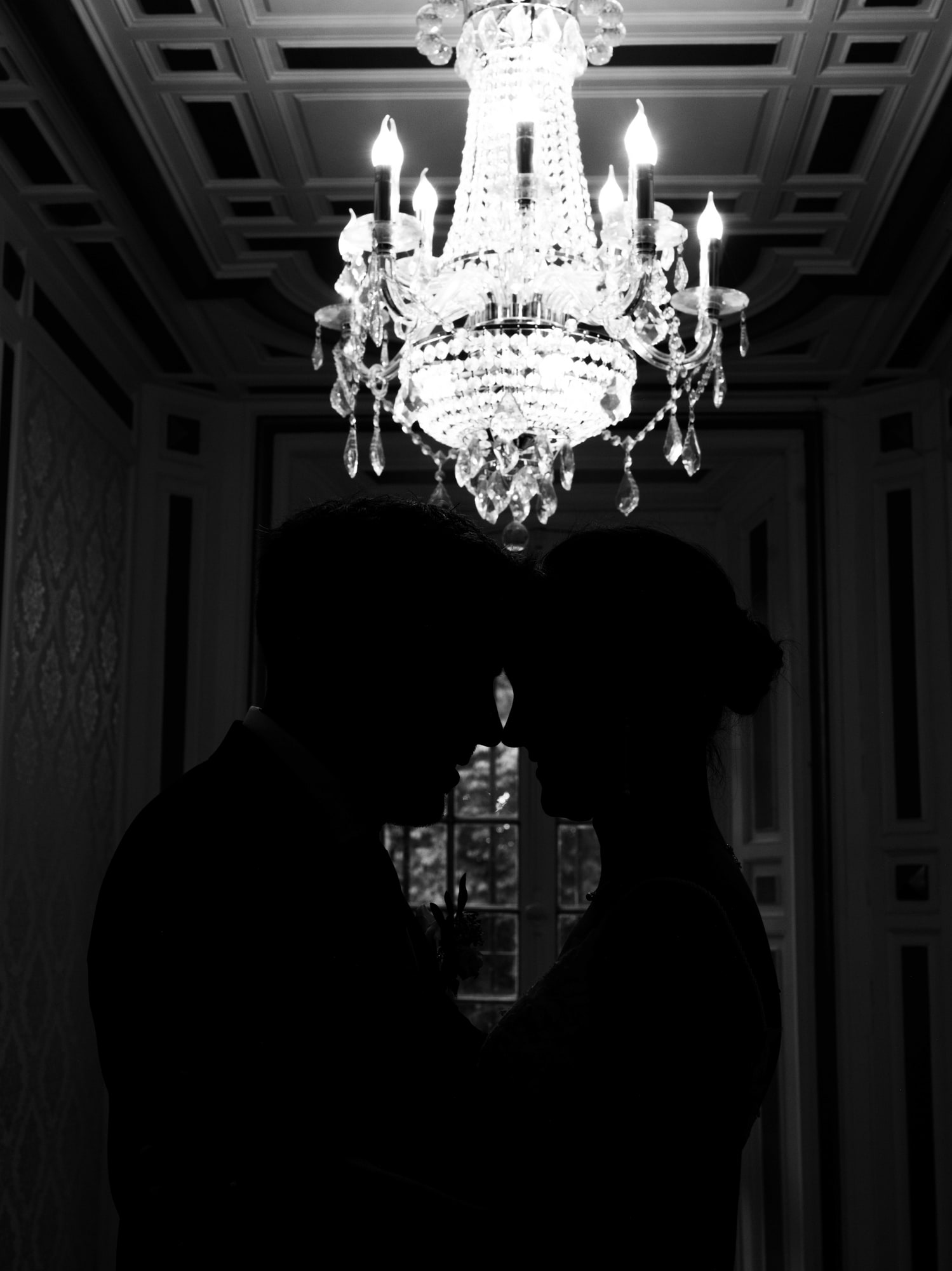 Silhouette des mariés sous le lustre du château, en noir et blanc, mariage au Château de Moliens, par Jean-Baptiste Argyre (Jaysphotography)
