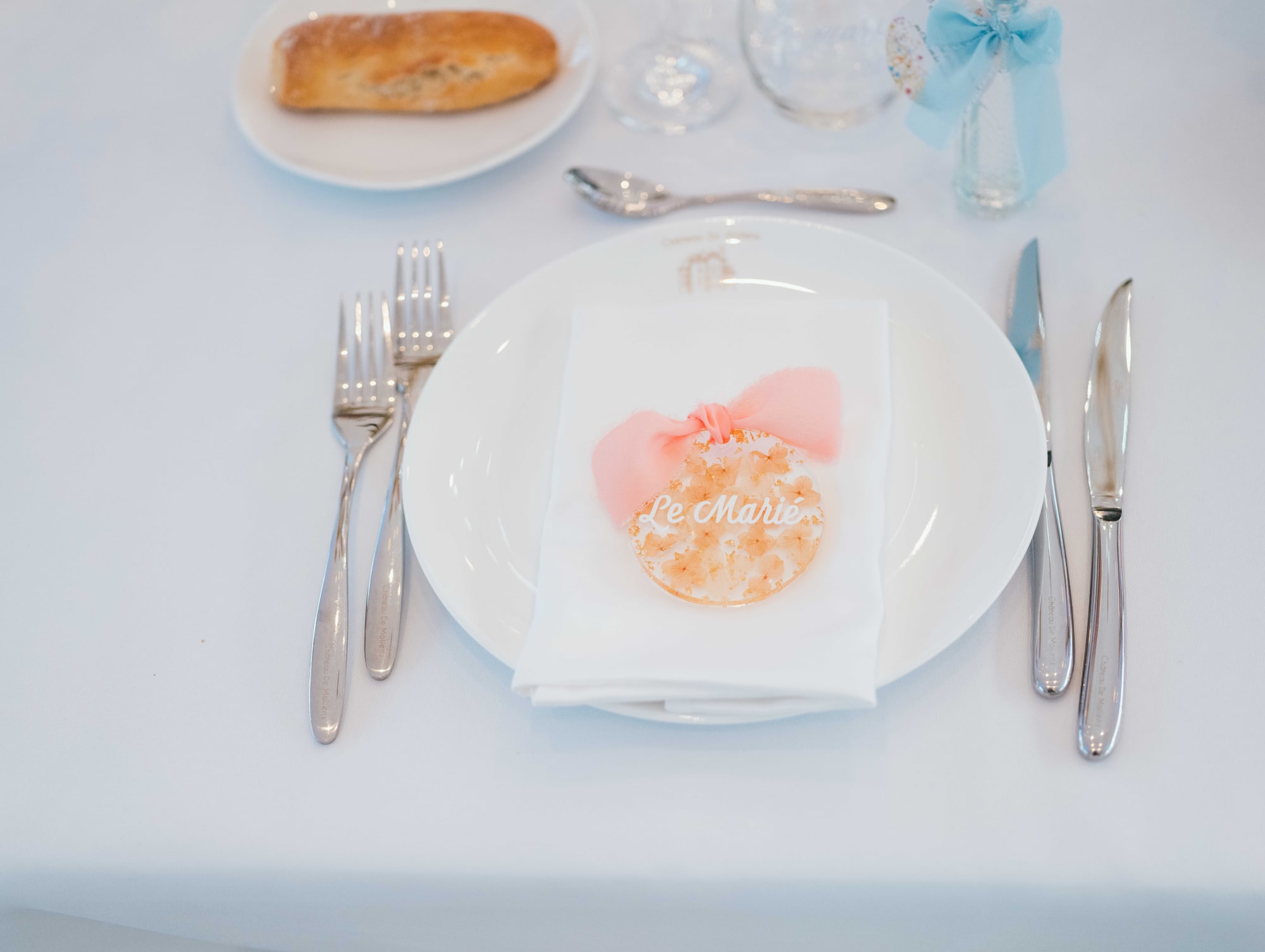 Assiette du dîner avec macaron personnalisé et nœud bleu ciel, mariage au Château de Moliens, par Jean-Baptiste Argyre (Jaysphotography)
