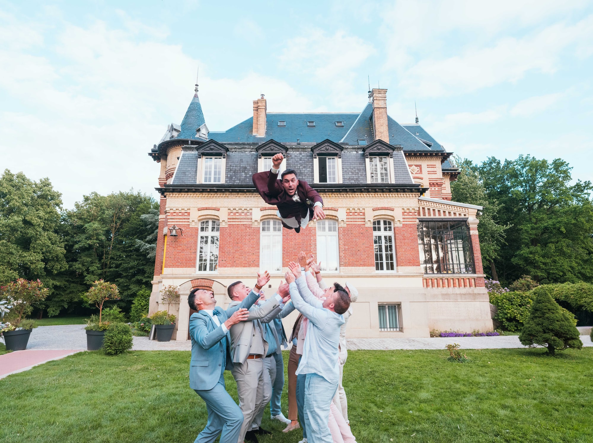 Jonathan lancé dans les airs par ses amis devant le château, mariage au Château de Moliens, par Jean-Baptiste Argyre (Jaysphotography)