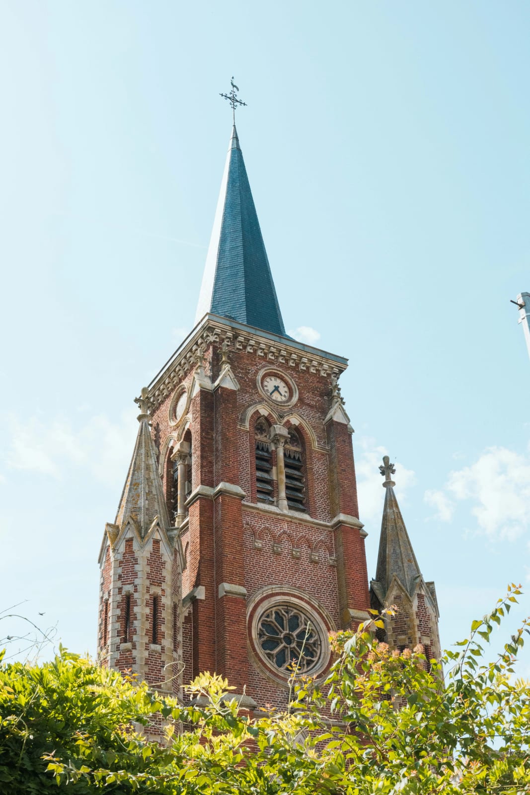 Clocher en brique de l'église de Saint-Remy-en-l'Eau sous le ciel bleu de juin, mariage au Valescourt (Oise), par Jean-Baptiste Argyre (Jaysphotography)
