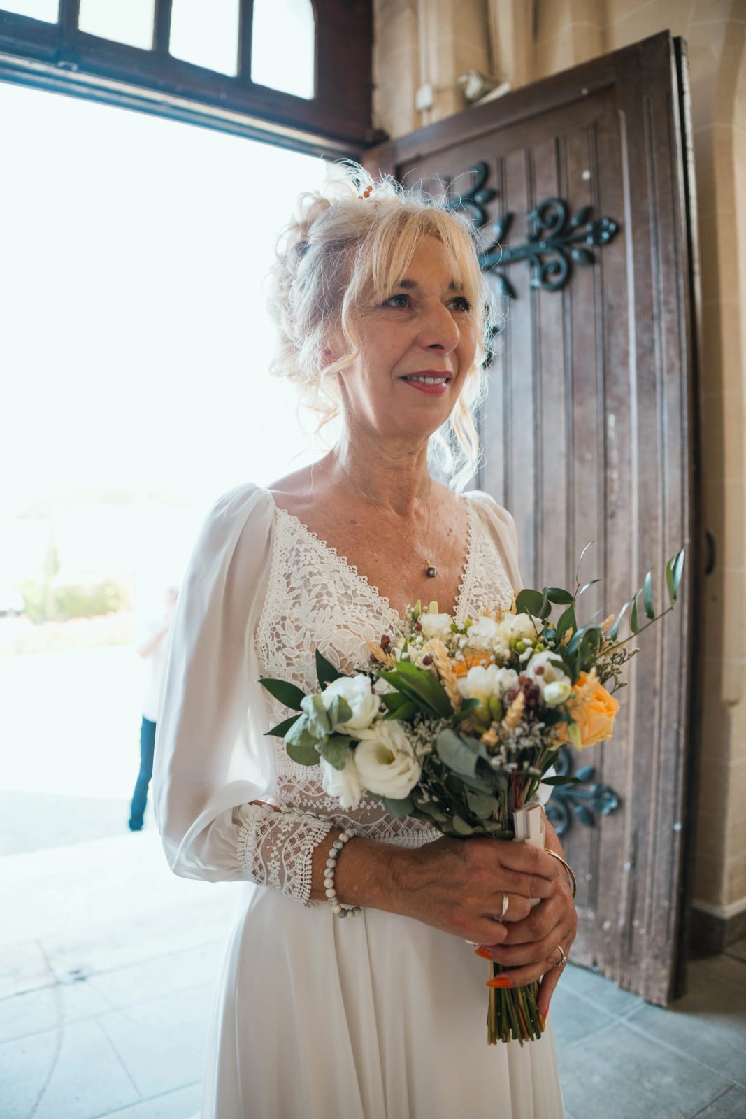 Portrait de Corinne, bouquet champêtre en main, à l'entrée de l'église, mariage au Valescourt (Oise), par Jean-Baptiste Argyre (Jaysphotography)