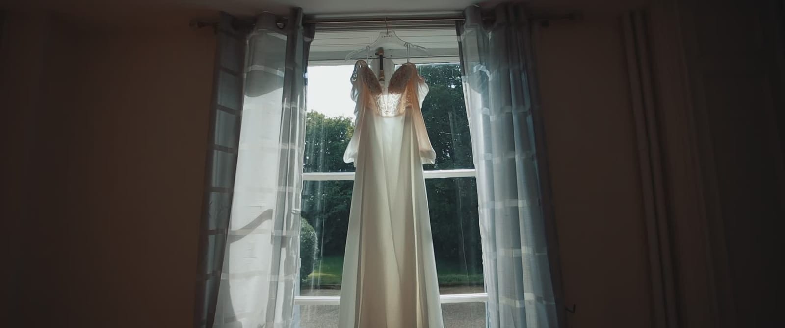 La robe de mariée de Delphine suspendue devant la fenêtre d'une suite du Château de Santeny, mariage au Château de Santeny, par Jean-Baptiste Argyre (Jaysphotography)