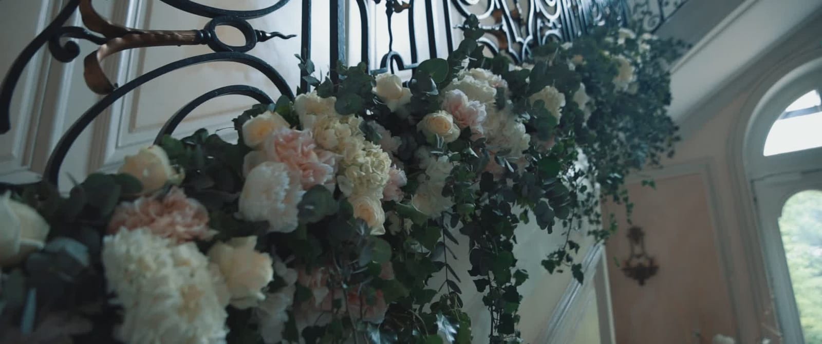 Roses, hortensias et eucalyptus habillant la rampe en fer forgé de l'escalier du château, mariage au Château de Santeny, par Jean-Baptiste Argyre (Jaysphotography)
