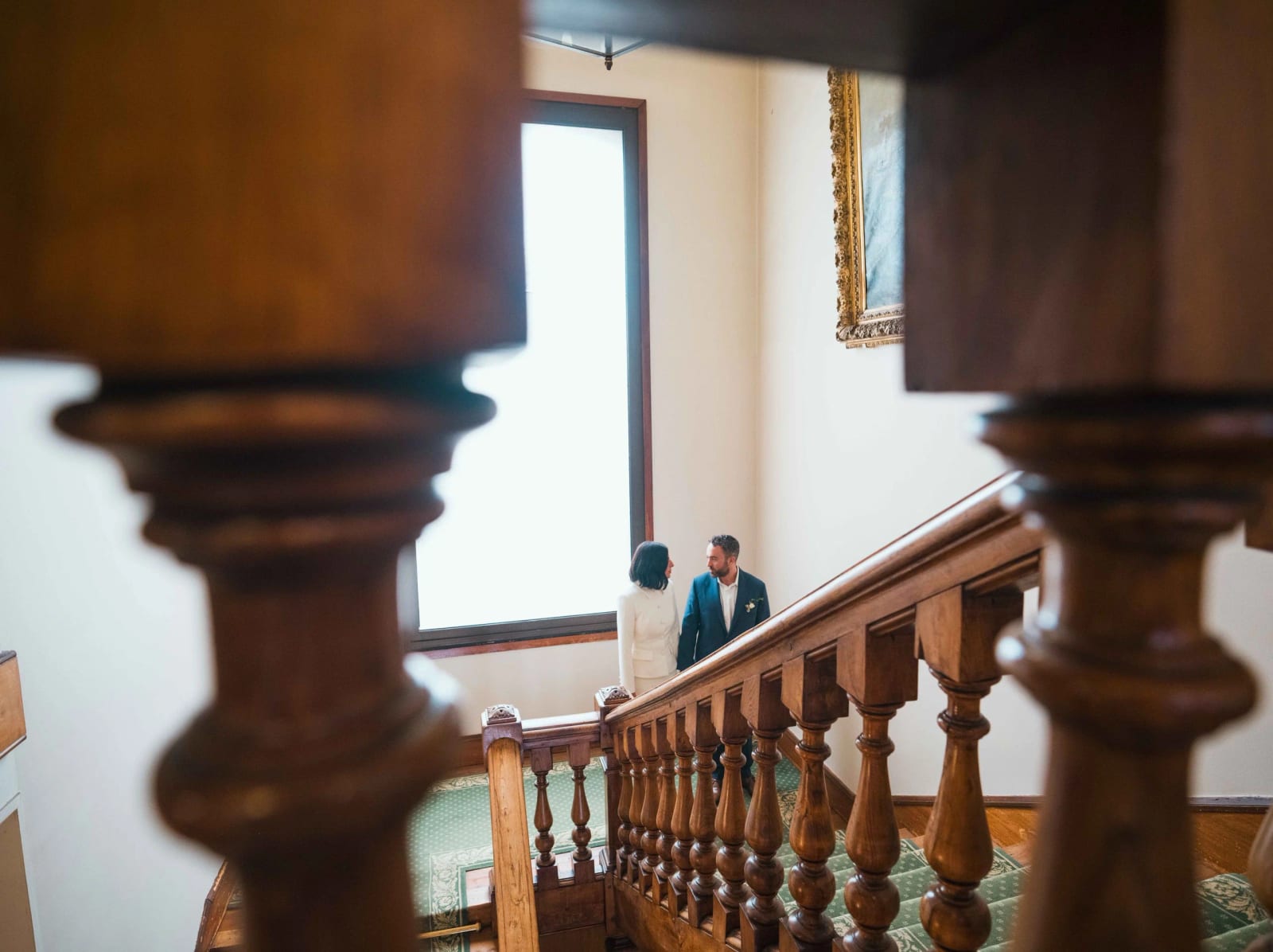 Les mariés sur le palier du grand escalier de la mairie de Deauville, vus à travers des balustres de bois tourné, mariage au Pavillon des Bains, Deauville, par Jean-Baptiste Argyre (Jaysphotography)