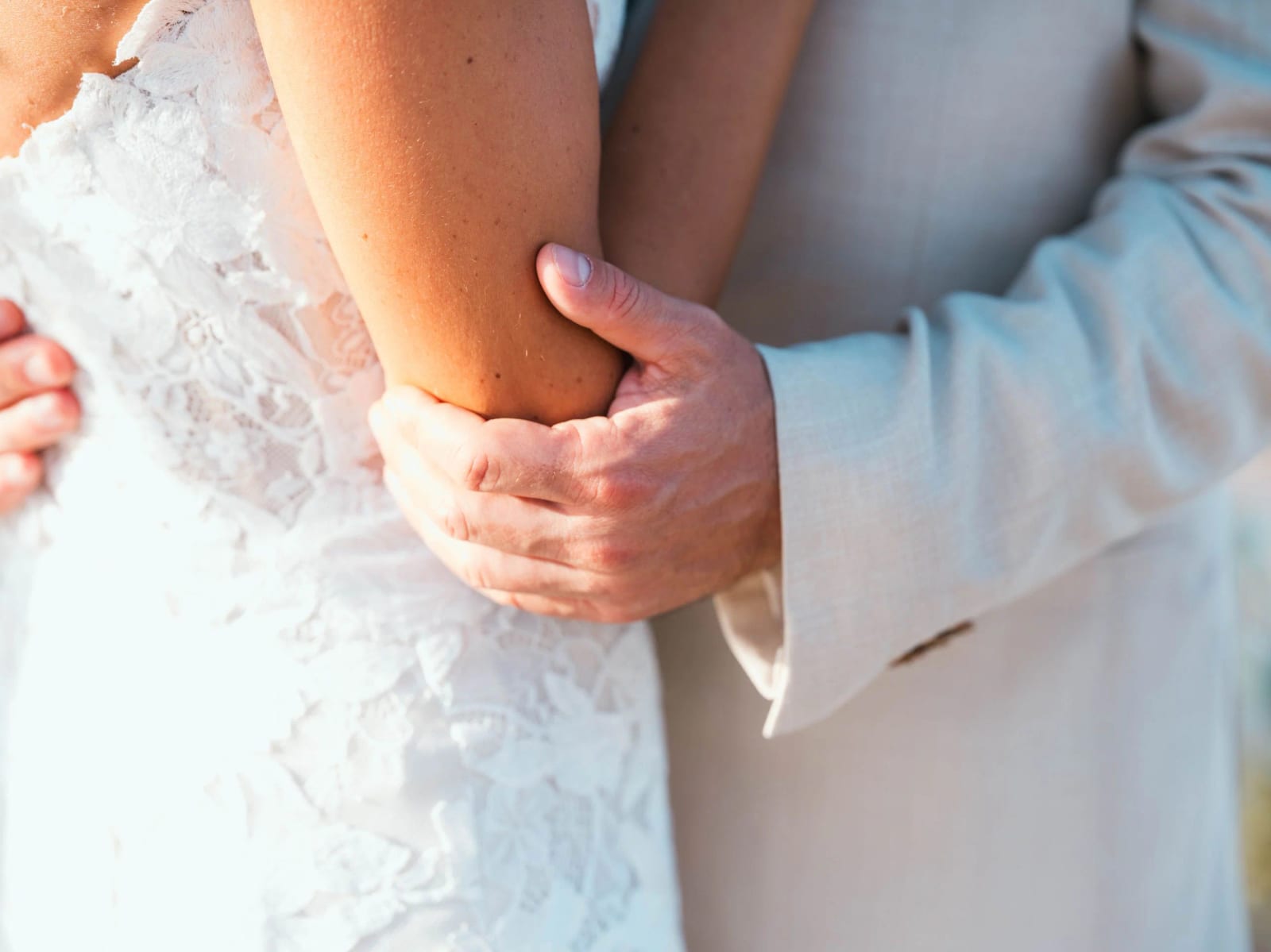 Gros plan sur la main du marié posée sur le bras de la mariée, dentelle et costume beige, mariage au Pavillon des Bains, Deauville, par Jean-Baptiste Argyre (Jaysphotography)