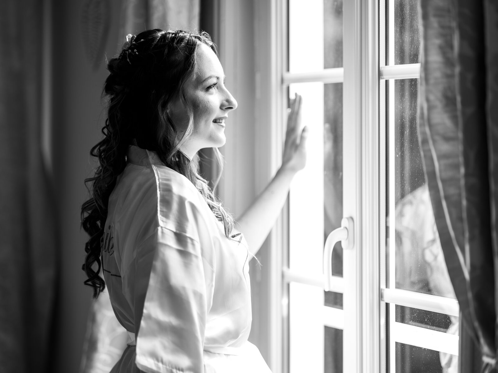Portrait noir et blanc d'Émilie en peignoir face à la fenêtre avant la cérémonie — mariage au Château de Naours, par Jean-Baptiste Argyre (Jaysphotography)