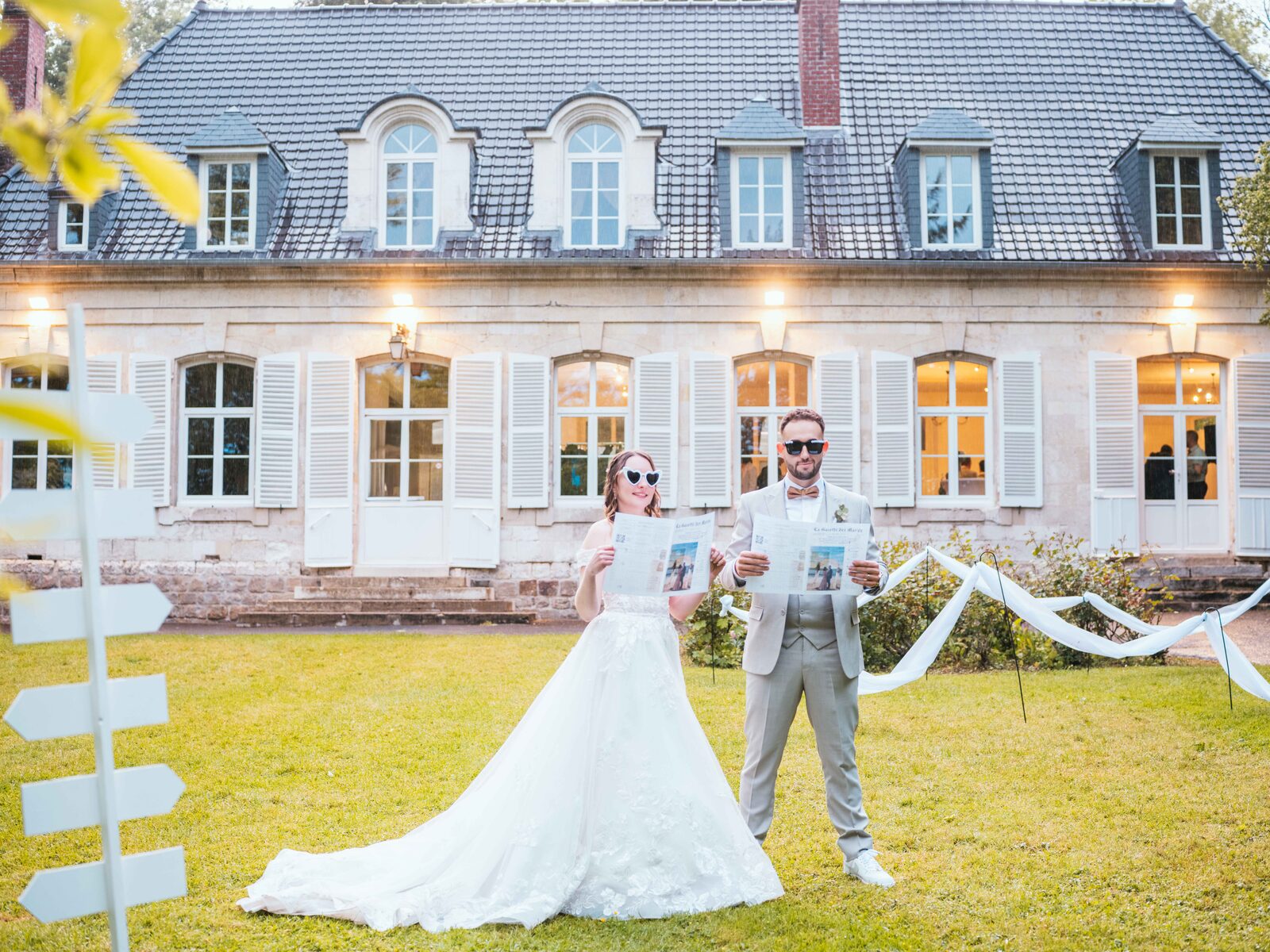 Grégory et Émilie devant la façade éclairée du château à la golden hour avec La Gazette des Mariés — mariage au Château de Naours, par Jean-Baptiste Argyre (Jaysphotography)