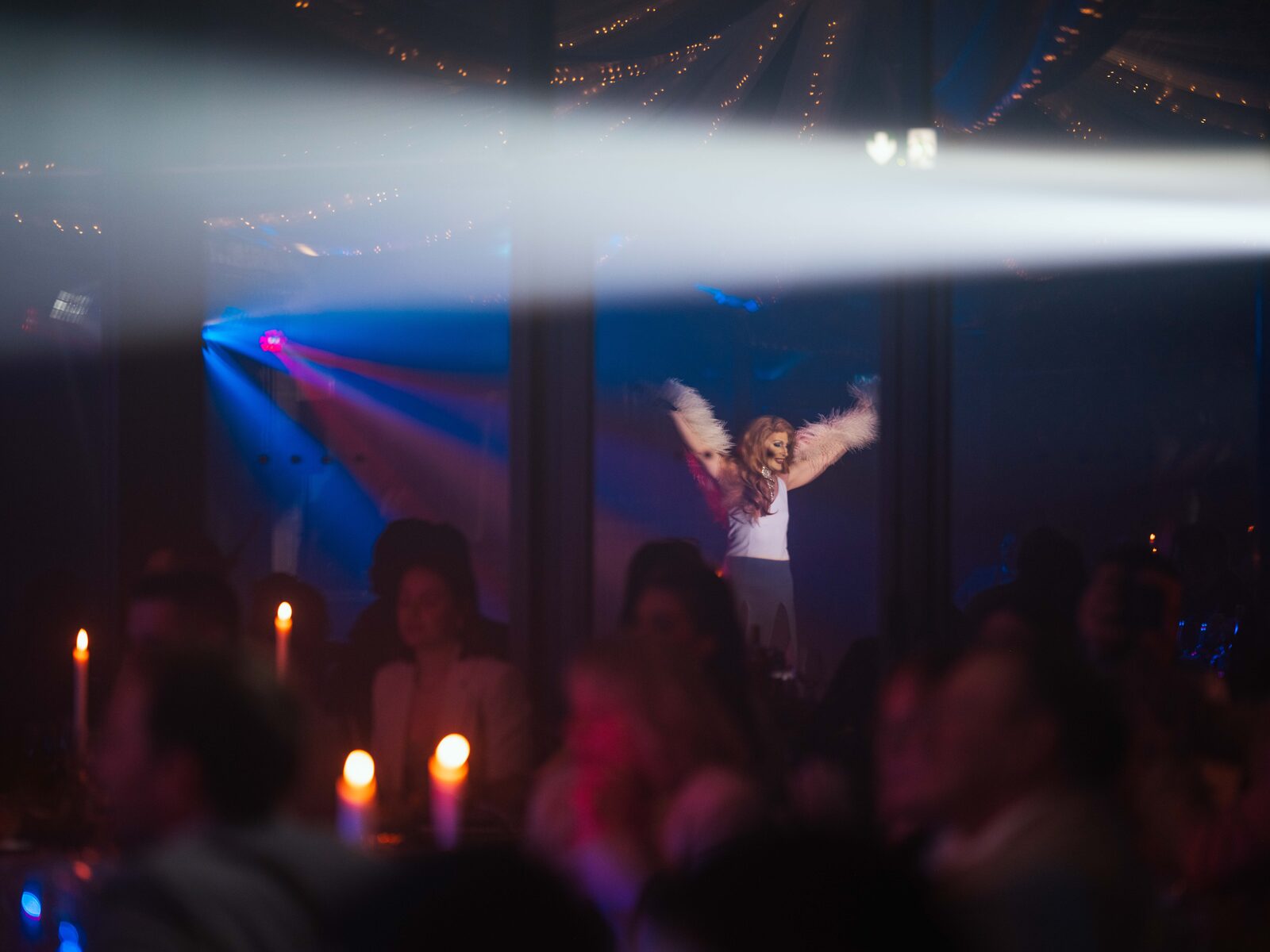 Show des transformistes, performeuse bras levés, vu depuis la salle aux bougies — mariage au Château de Naours, par Jean-Baptiste Argyre (Jaysphotography)