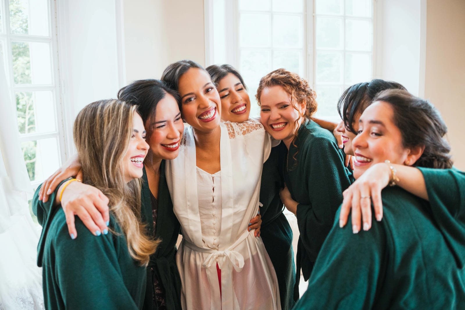 Ana enlacée par ses demoiselles d'honneur en peignoirs vert émeraude, rires complices serrés les uns contre les autres, mariage au Domaine d'Orgival, par Jean-Baptiste Argyre (Jaysphotography)