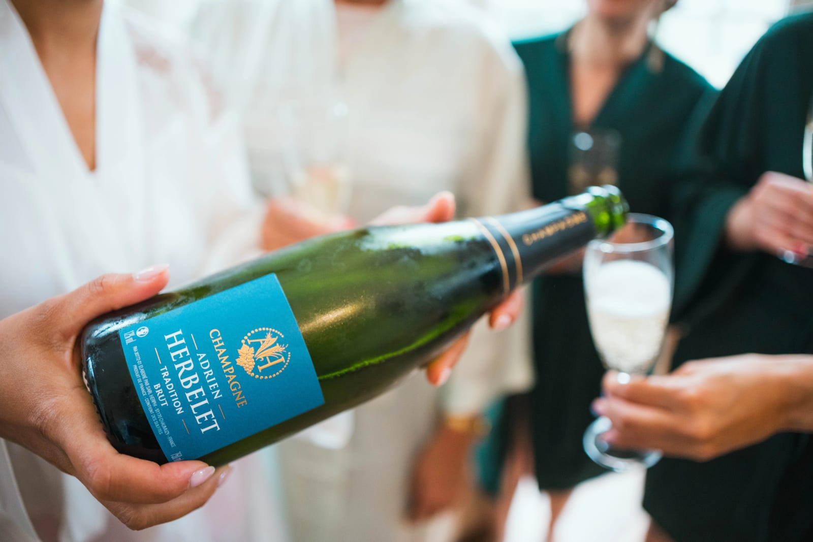 Gros plan sur une bouteille de champagne Adrien Herbelet servie dans une flûte pendant les préparatifs de la mariée, mariage au Domaine d'Orgival, par Jean-Baptiste Argyre (Jaysphotography)