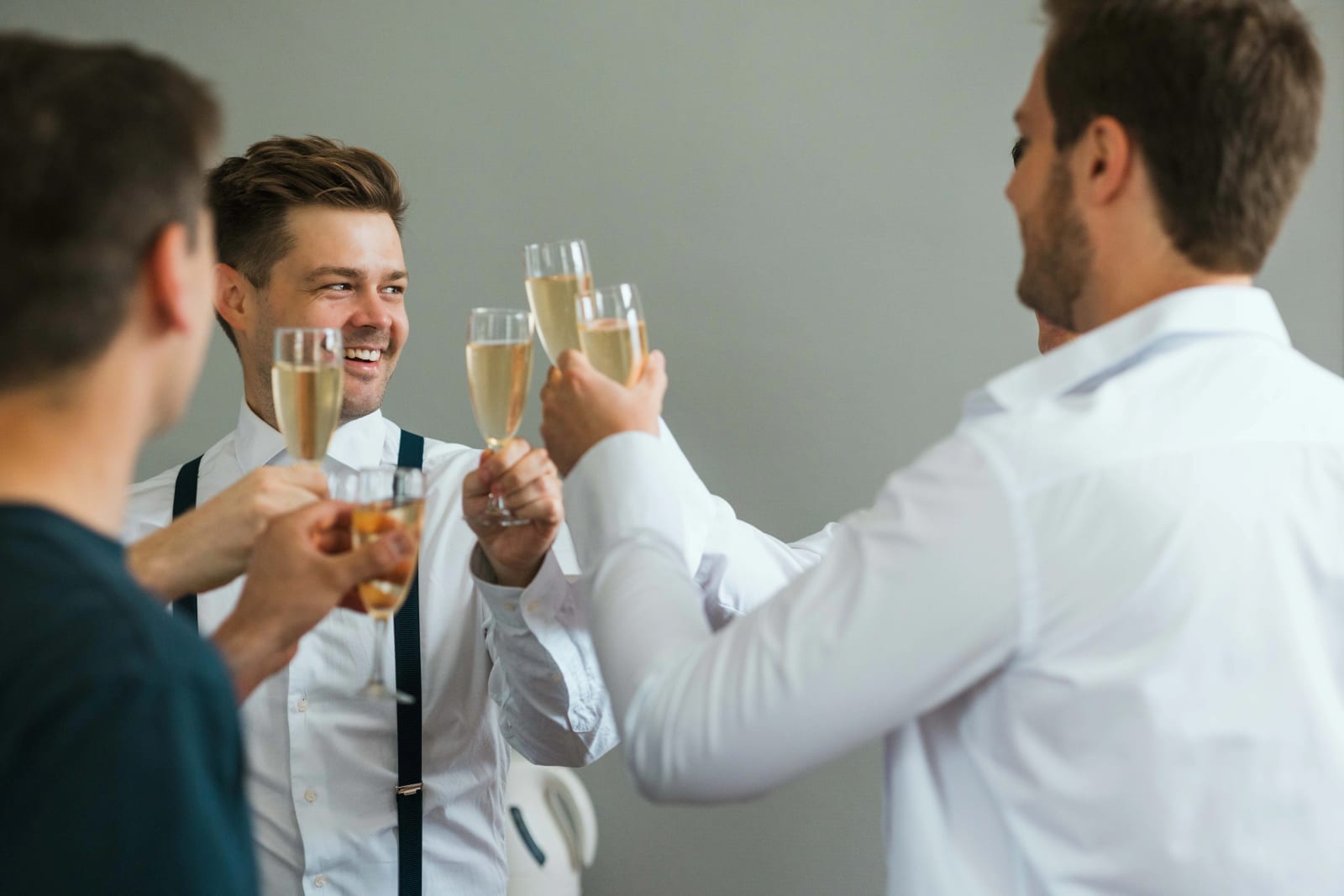 Des hommes en chemise blanche trinquent au champagne pendant les préparatifs du marié, mariage au Domaine d'Orgival, par Jean-Baptiste Argyre (Jaysphotography)