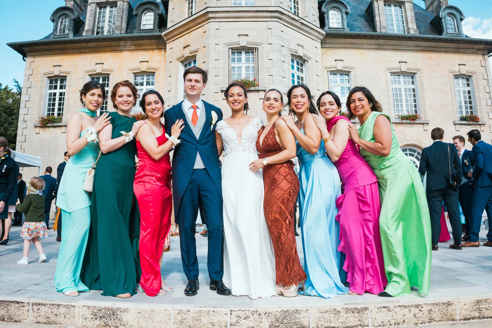 Ana entourée de ses demoiselles d'honneur en robes longues multicolores, devant la façade du château du Domaine d'Orgival, mariage au Domaine d'Orgival, par Jean-Baptiste Argyre (Jaysphotography)