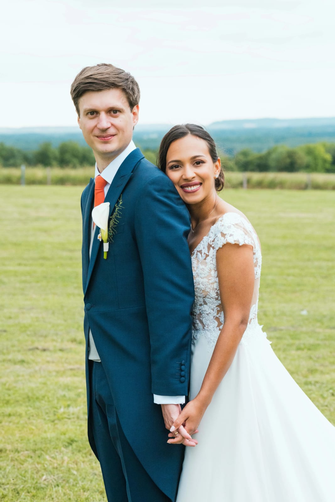 Ana, appuyée sur l'épaule de Guillaume, lui tient la main dans la prairie, tous deux souriant à l'objectif, mariage au Domaine d'Orgival, par Jean-Baptiste Argyre (Jaysphotography)