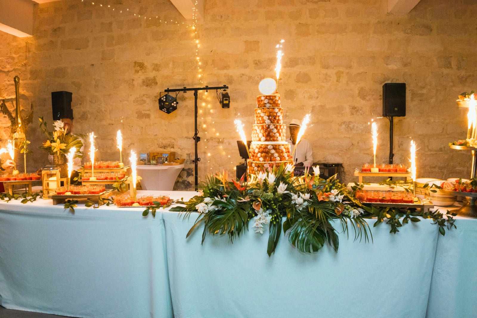 Table de dessert au Domaine d'Orgival : pièce montée de choux et tartes aux fruits illuminées de fontaines d'étincelles, garniture de feuillage tropical, mariage au Domaine d'Orgival, par Jean-Baptiste Argyre (Jaysphotography)